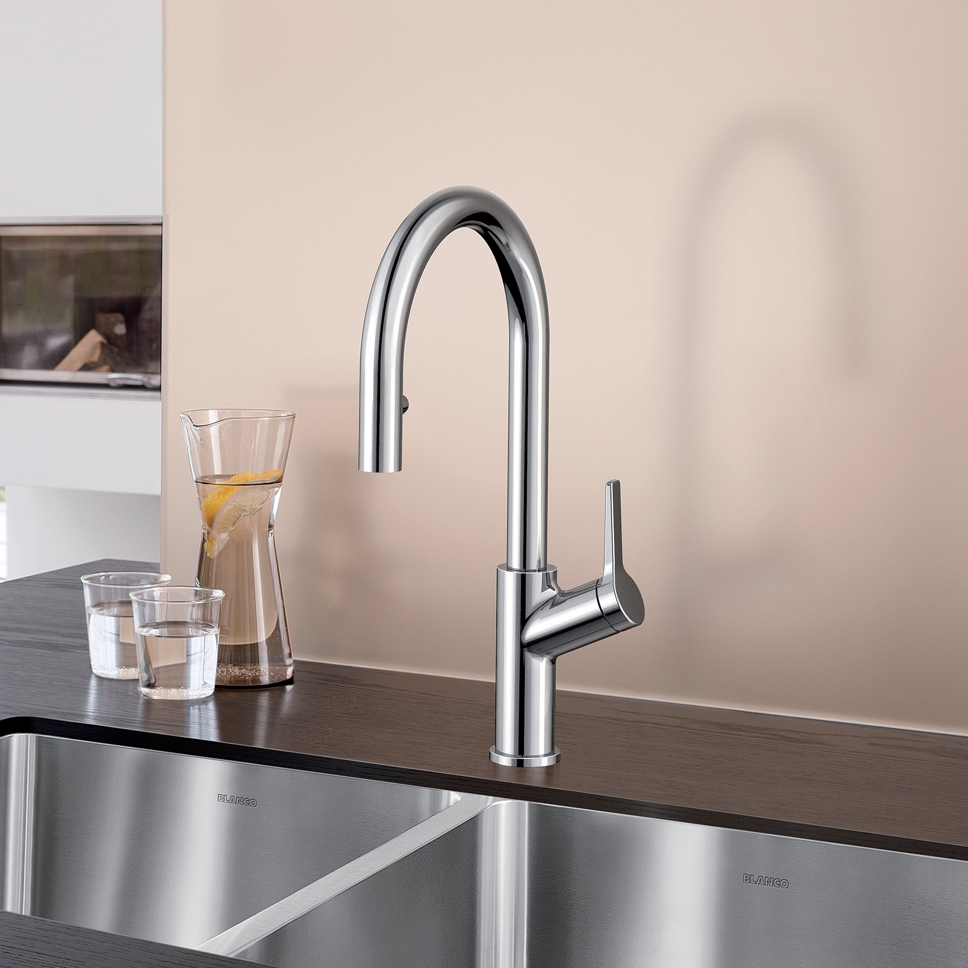 Chrome pull-down kitchen faucet with tall arched spout and single lever handle mounted on dark countertop.