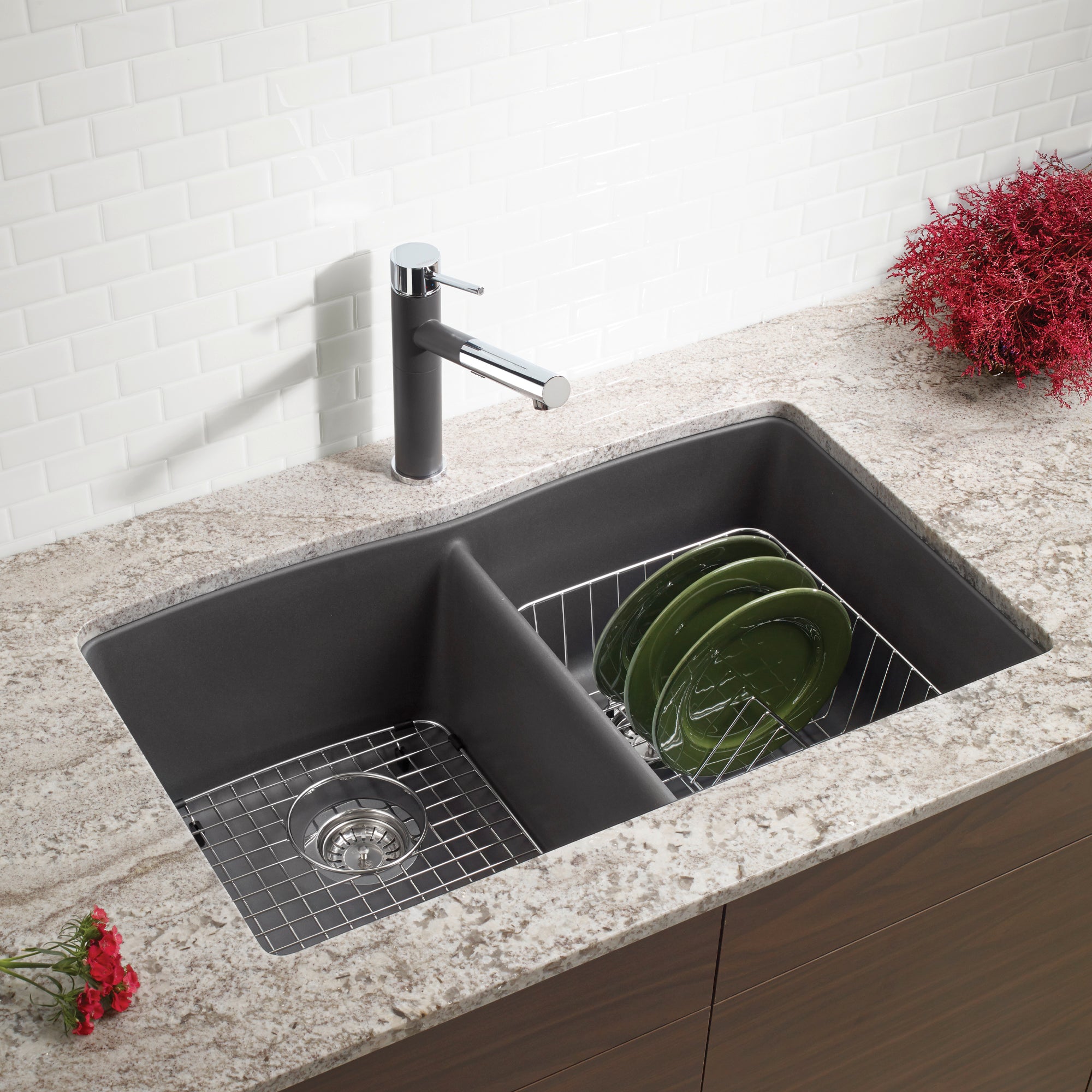 Cinder-colored double bowl undermount sink with wire grids and black faucet installed in countertop.