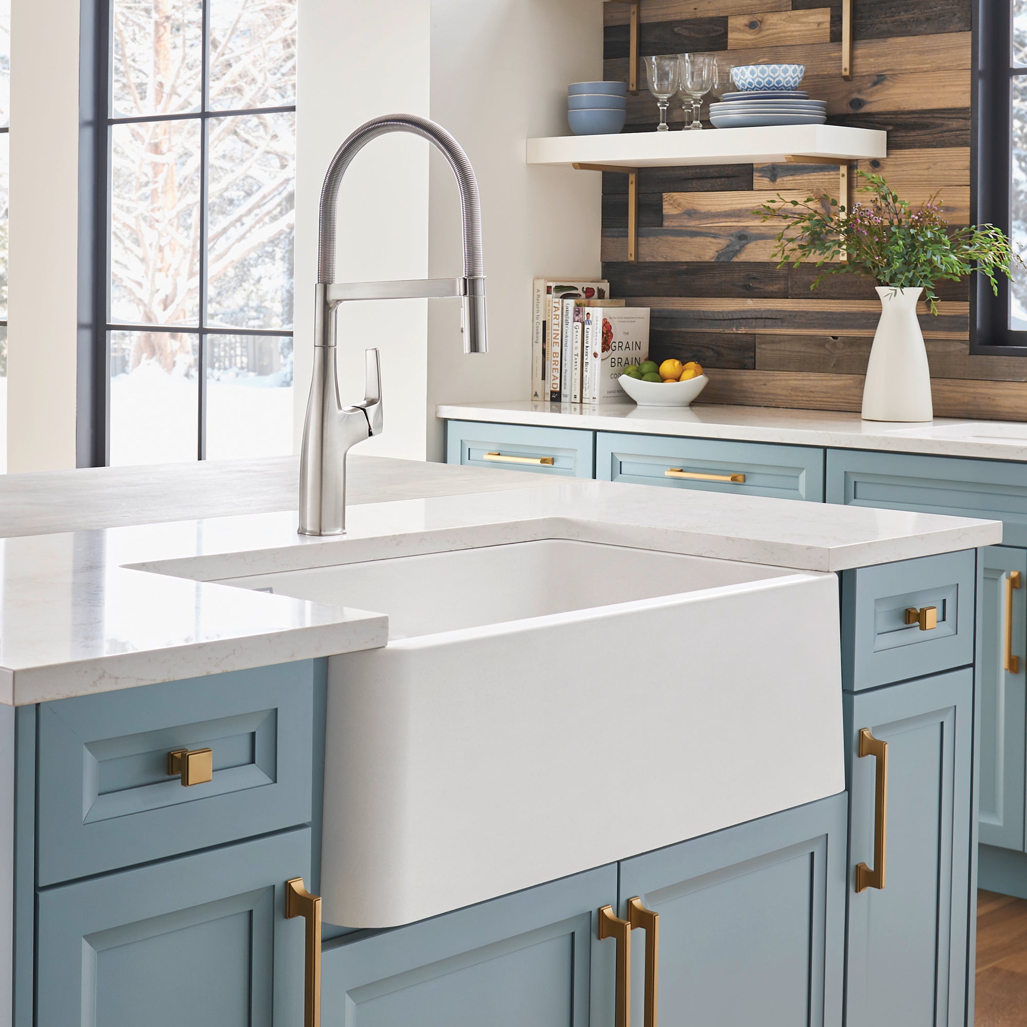 White double bowl farmhouse sink with low divide and arched pull-down faucet in kitchen.