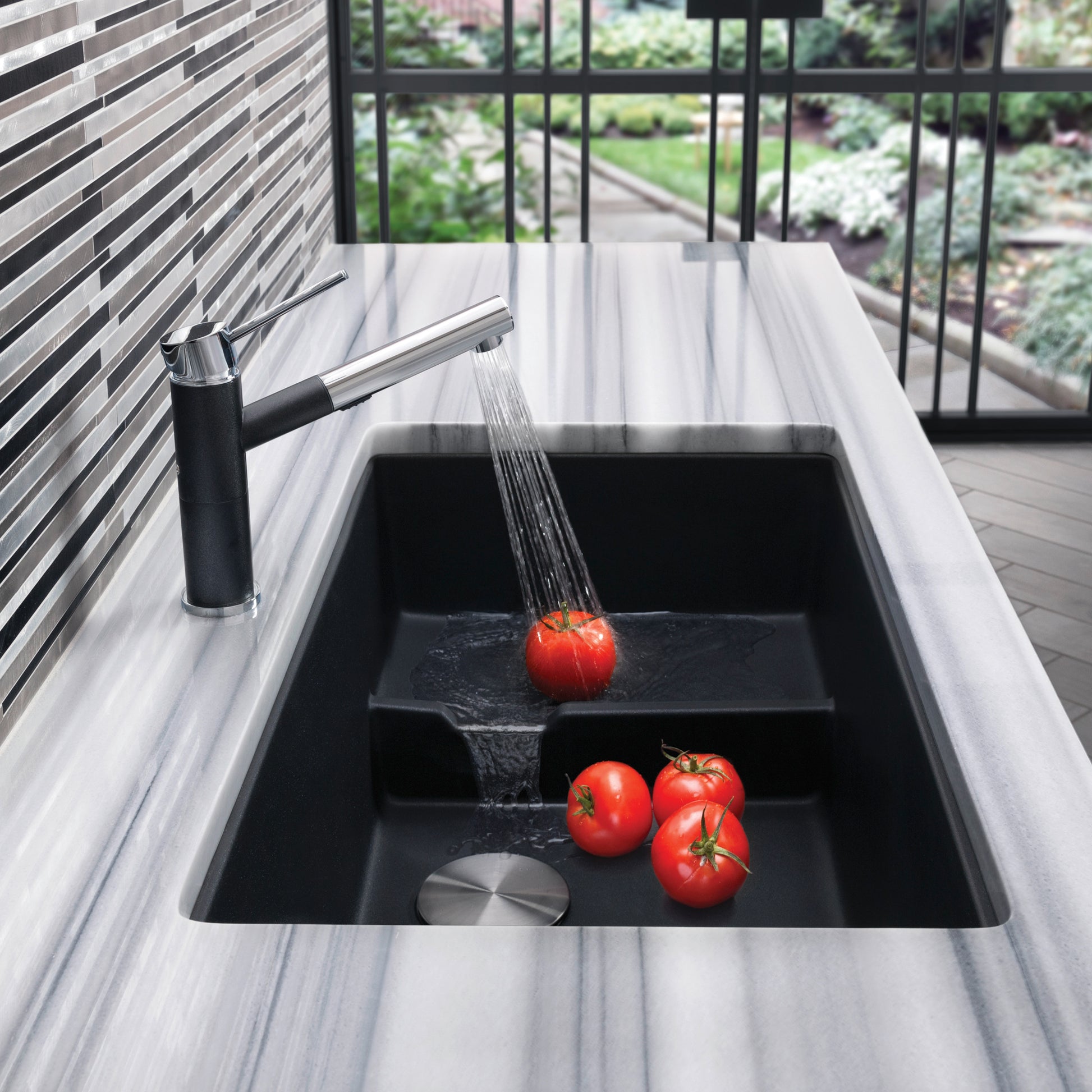 Anthracite undermount sink with black pull-down faucet and cascade spout in modern kitchen.