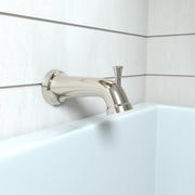 Polished nickel tub spout with diverter mounted on white tile wall above bathtub edge.