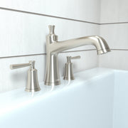 Brushed nickel three-hole roman tub faucet set with curved spout and lever handles mounted on white tile.