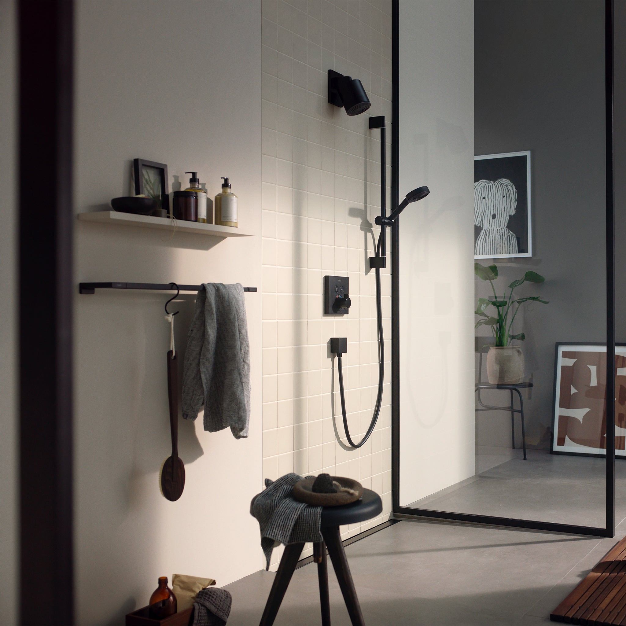 Matte black shower head mounted on bathroom wall with single-jet spray nozzle and adjustable handheld wand.