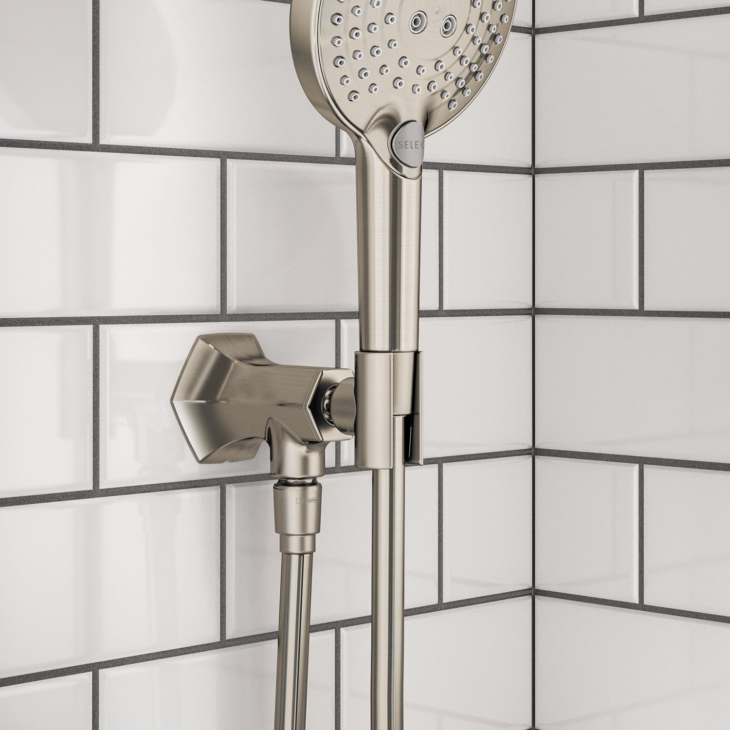 Brushed nickel handshower holder with outlet mounted on tile wall, holding perforated showerhead and hose.