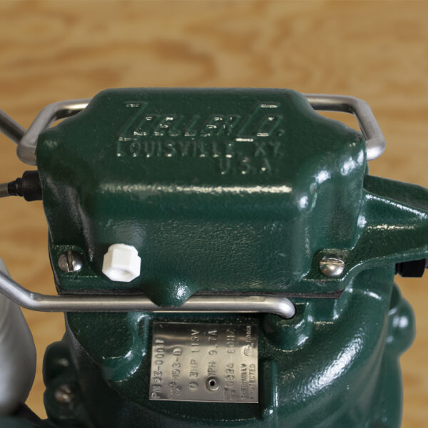Dark green cast iron submersible sump pump with silver metal handles and electrical cord attached.