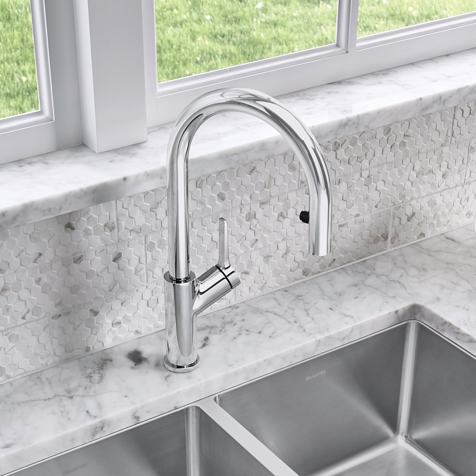 Chrome pull-down kitchen faucet with curved spout and single lever handle mounted on marble countertop above sink.