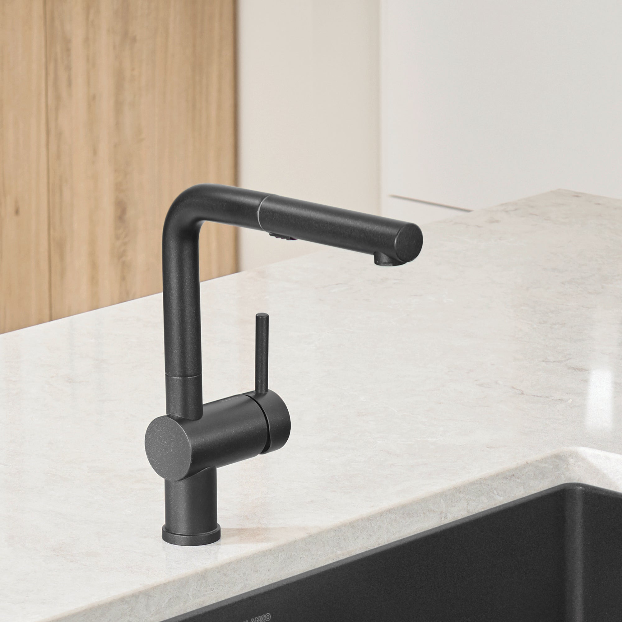 Anthracite pull-out kitchen faucet with single handle mounted on white countertop next to dark sink.