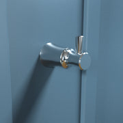 Chrome bathroom hook with cylindrical base and upright post mounted on blue wall.