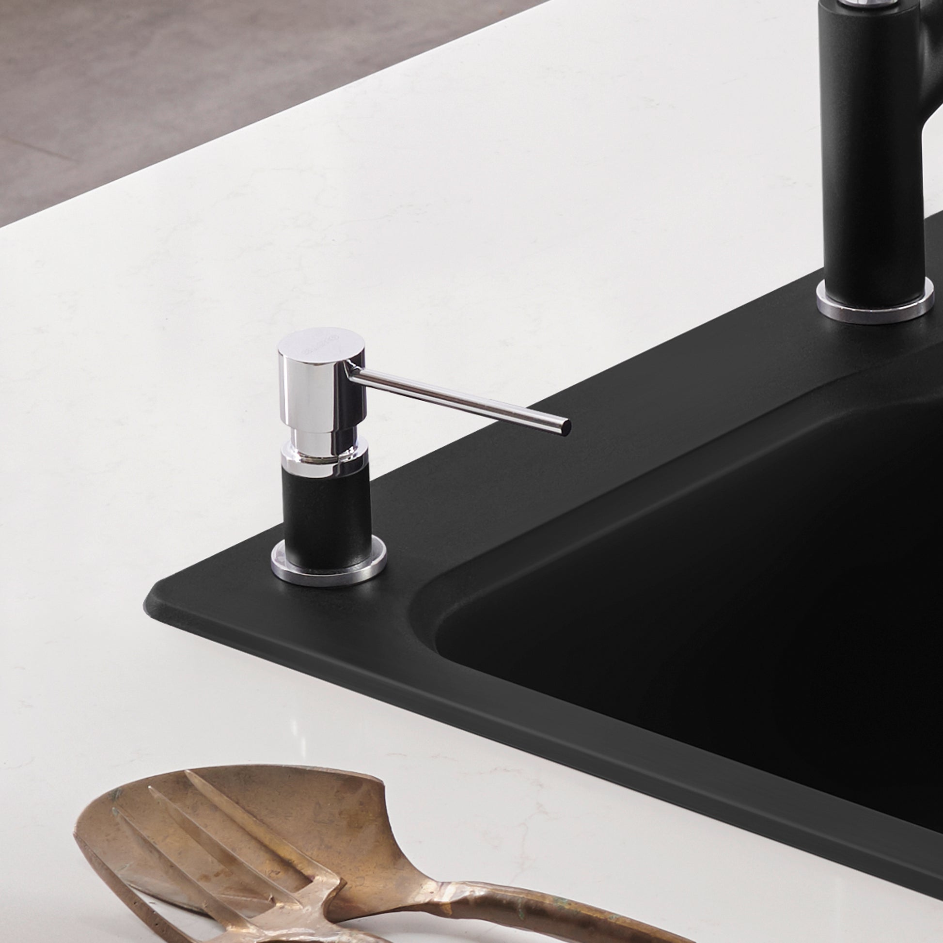 Chrome and coal black soap dispenser with cylindrical pump mounted on black sink countertop.
