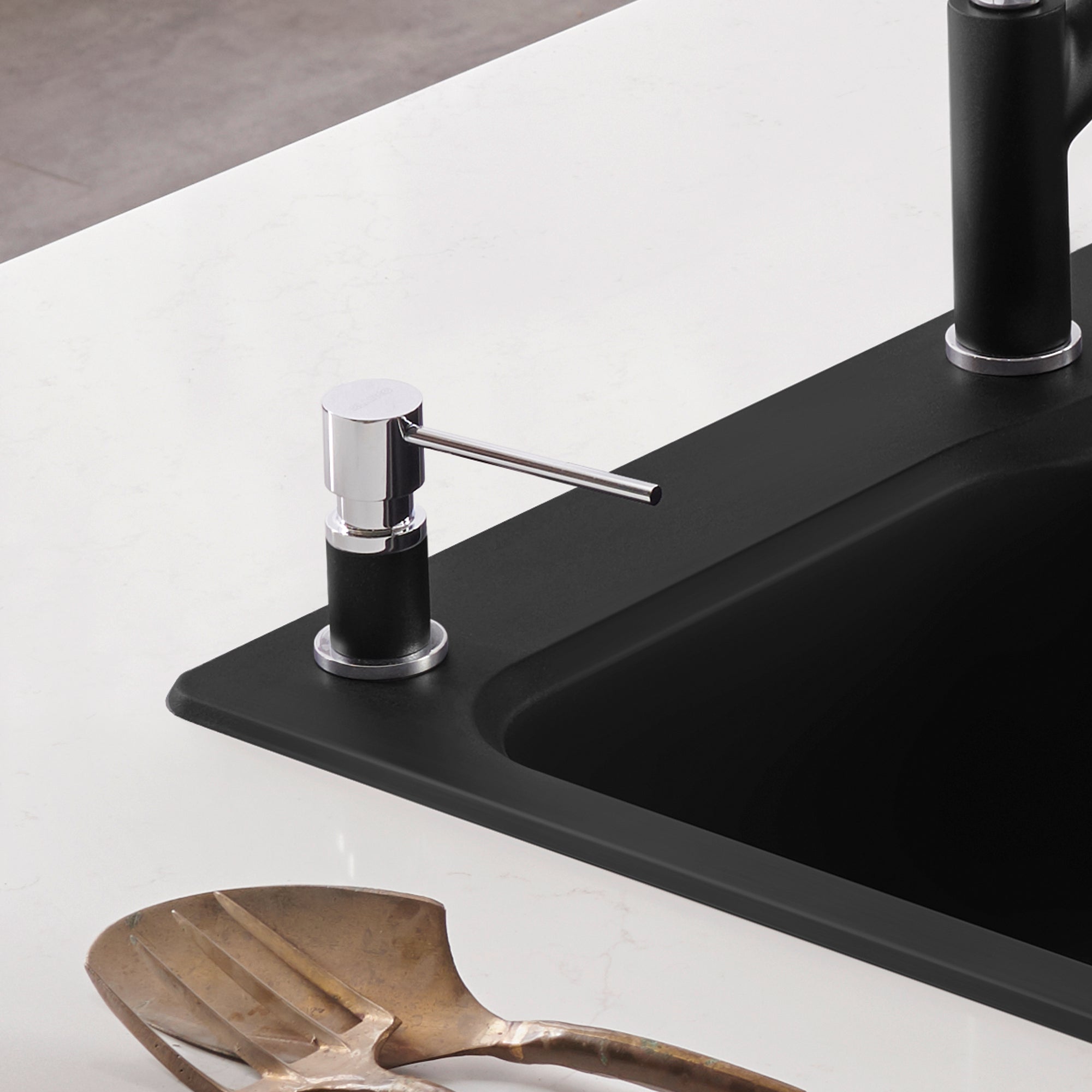Chrome and coal black soap dispenser with cylindrical pump mounted on black sink countertop.