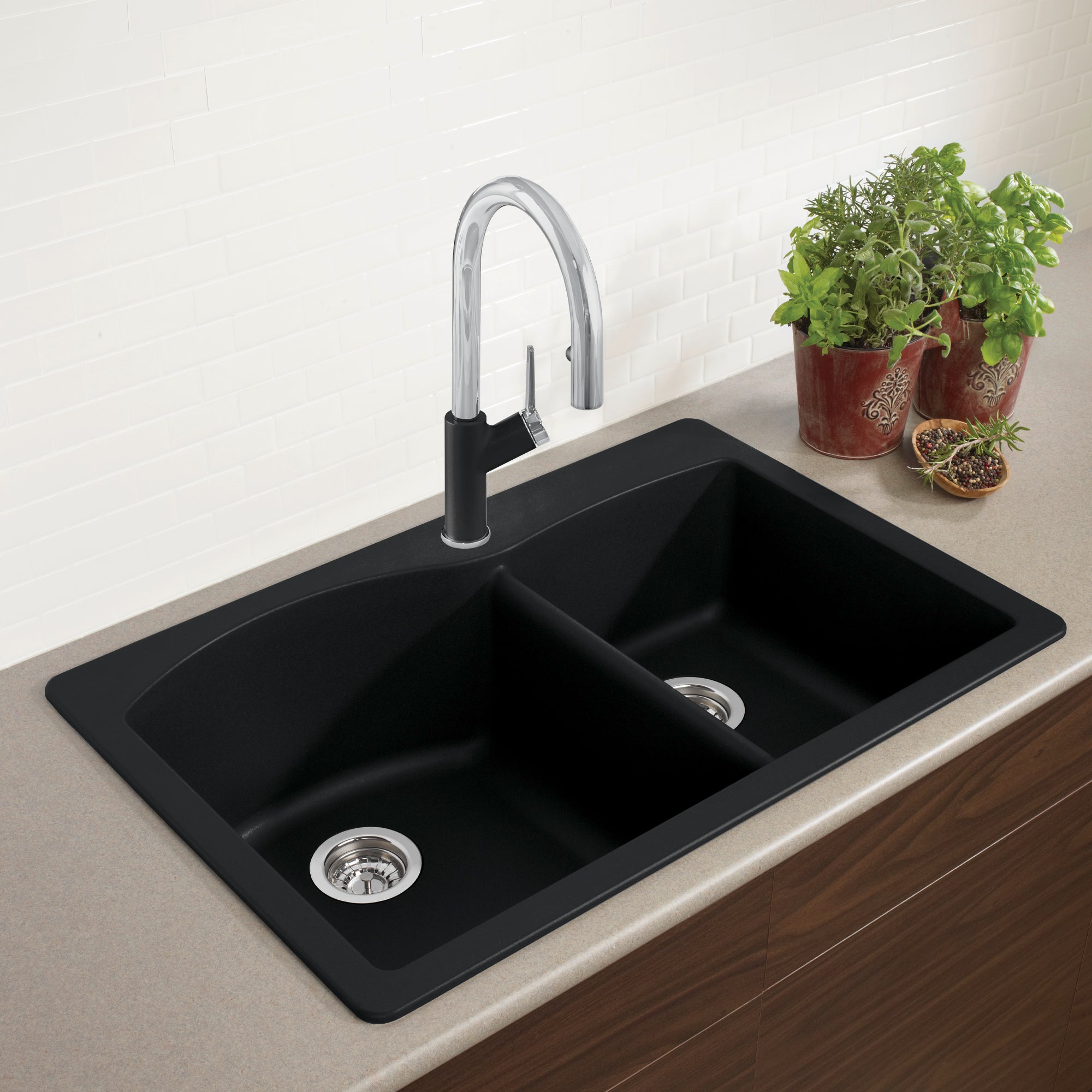 Anthracite drop-in kitchen sink with two unequal bowls, chrome pull-down faucet, and stainless steel strainers installed in c