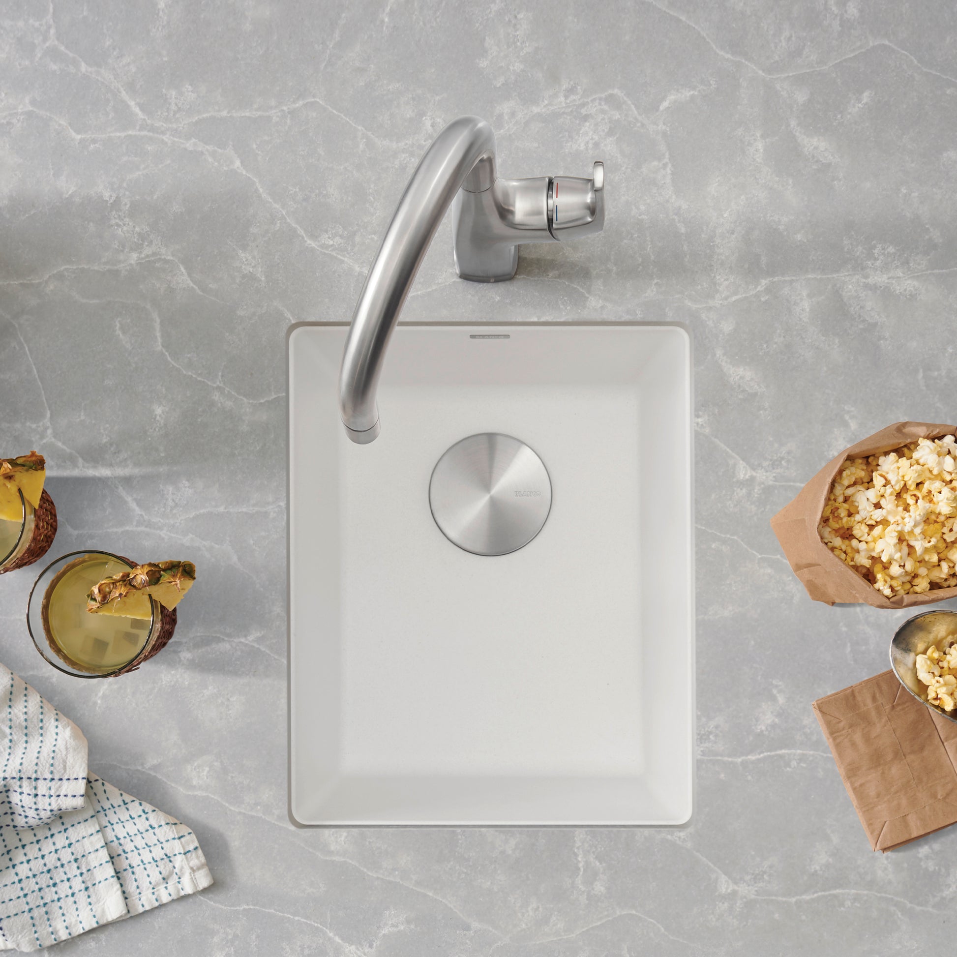 White rectangular undermount kitchen sink with chrome faucet and drain, viewed from above.