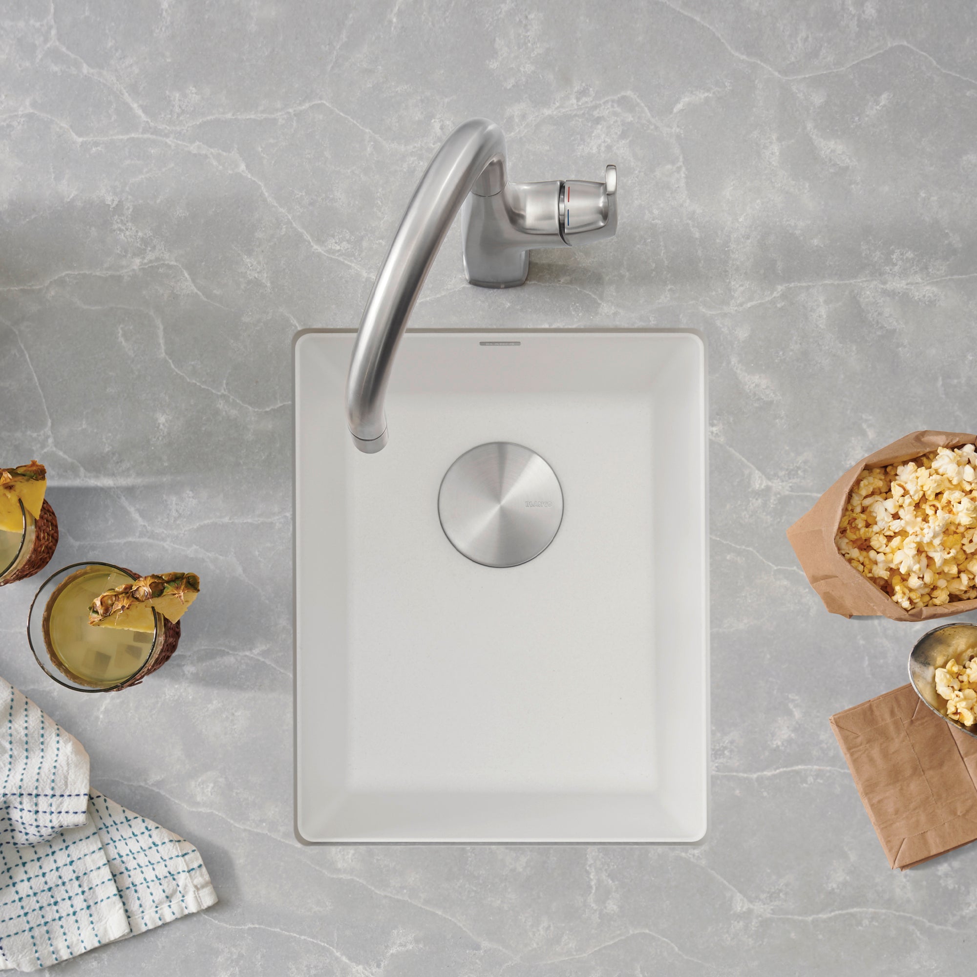 White rectangular undermount kitchen sink with chrome faucet and drain, viewed from above.