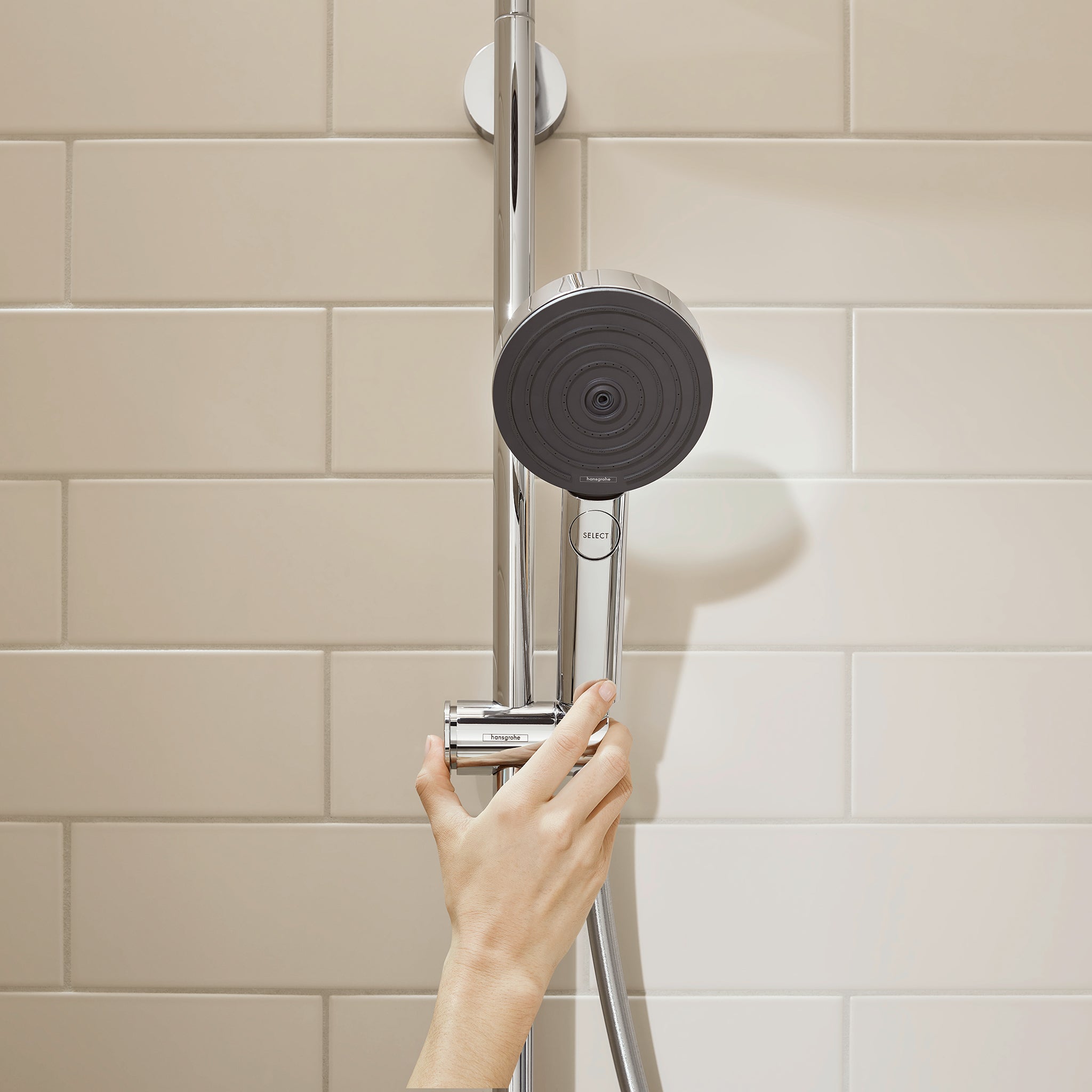 Brushed nickel wallbar shower set with black circular showerhead and handheld spray mounted on tiled wall.