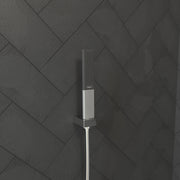 Chrome handheld shower head with rectangular baton design and perforated spray face mounted on wall tile.
