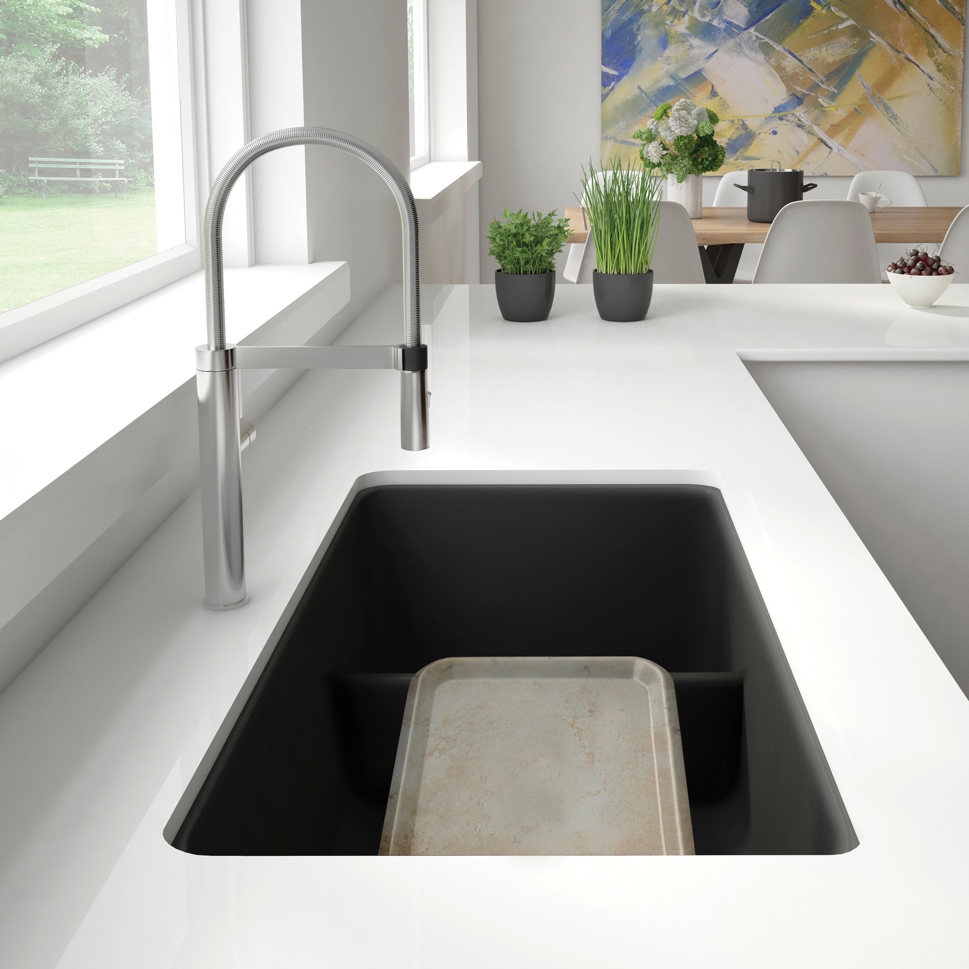 Anthracite undermount kitchen sink with low divider and arched stainless steel faucet installed in white countertop.