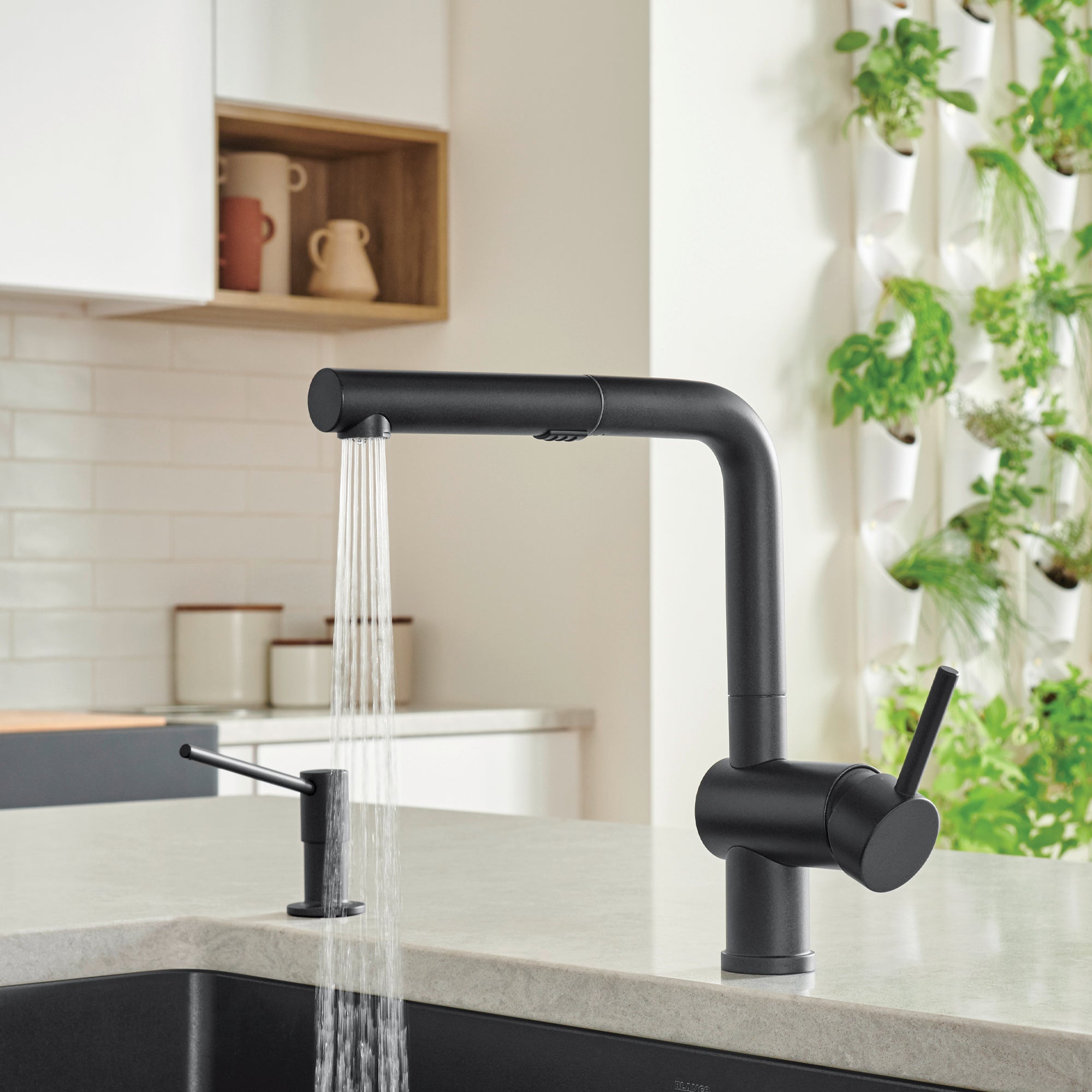 Coal black pull-out kitchen faucet with curved spout and single lever handle, installed above sink with water running.