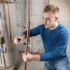 Man in blue shirt installing black handle on white plumbing fixture.