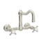 Polished nickel wall-mounted bridge kitchen faucet with column spout and curved handles.