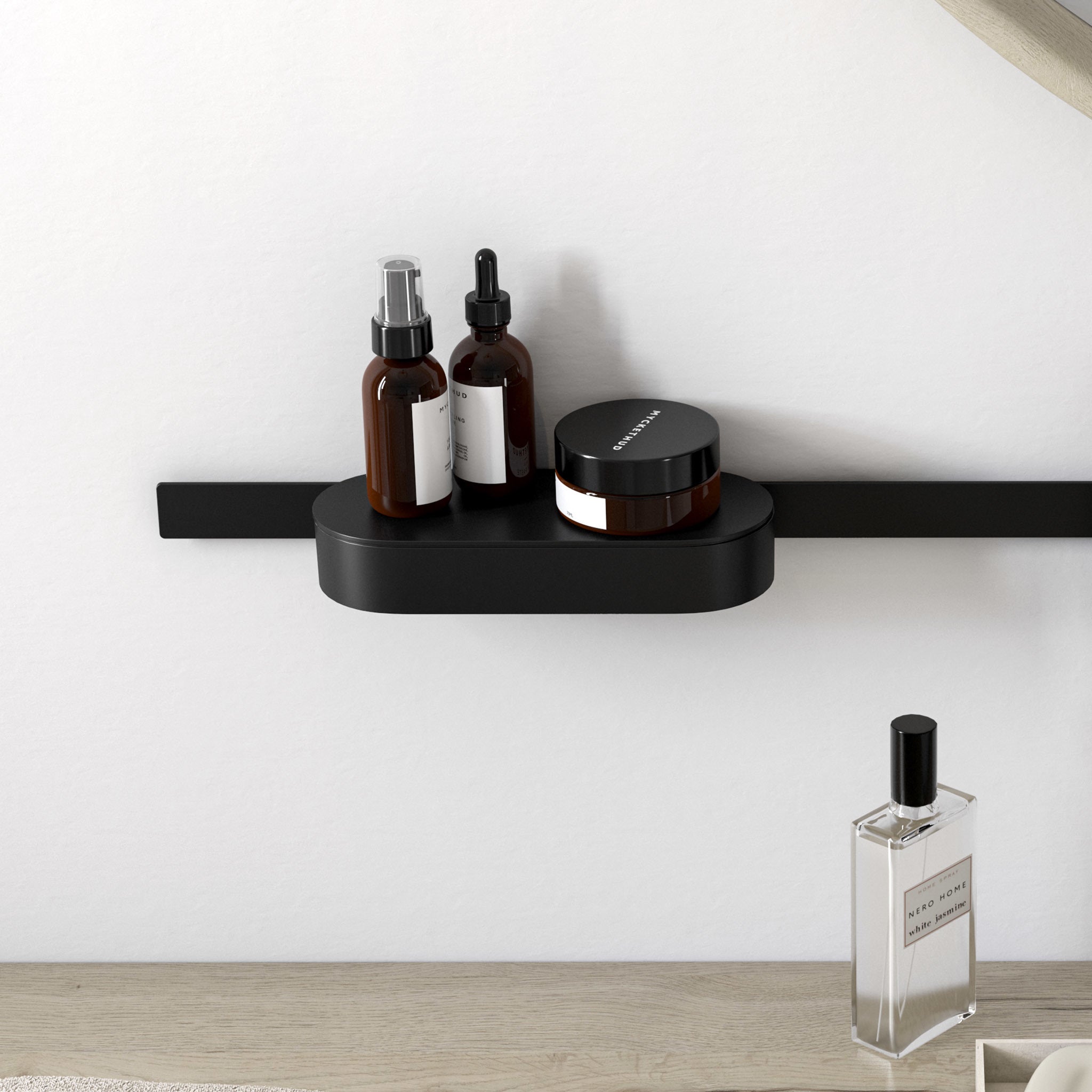 Matte black wall-mounted storage basket with rounded tray design holding brown glass bottles and containers.