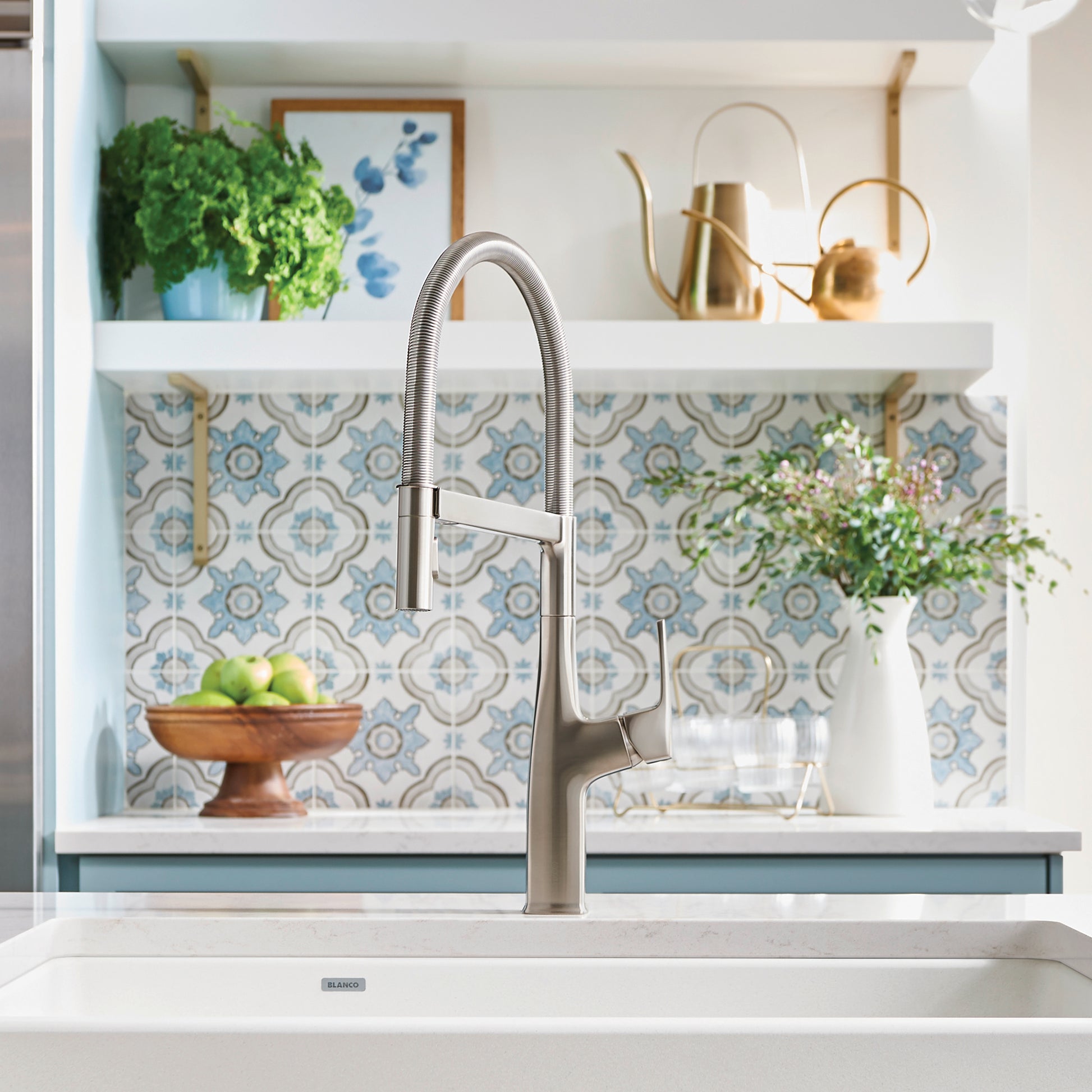 Stainless steel semi-pro kitchen faucet with flexible hose spray head mounted over white sink basin.