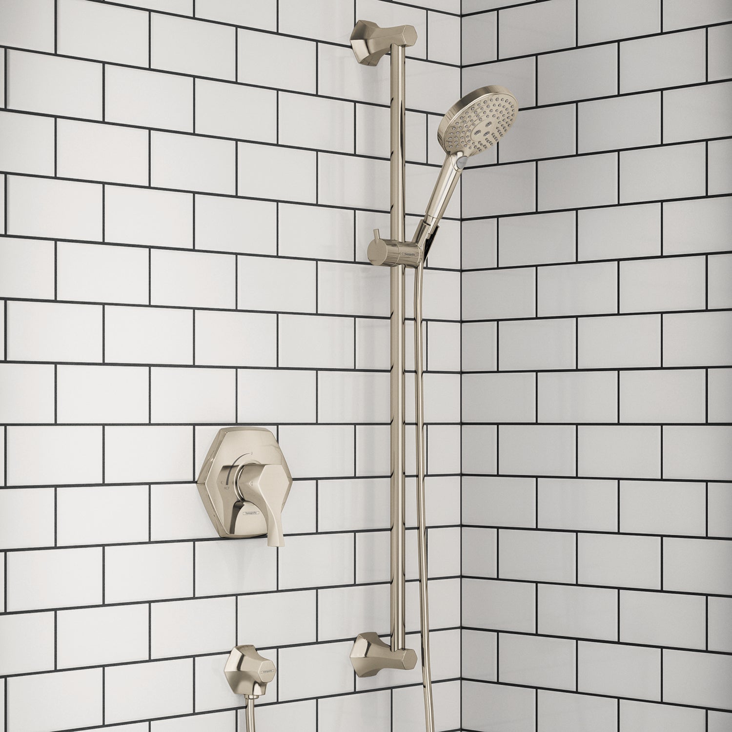 Polished nickel shower system mounted on subway tile wall with valve, handheld showerhead, and vertical bar.