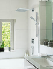 Chrome thermostatic shower set with square ceiling-mounted showerhead, handheld wand, and dual control handles on white tile 