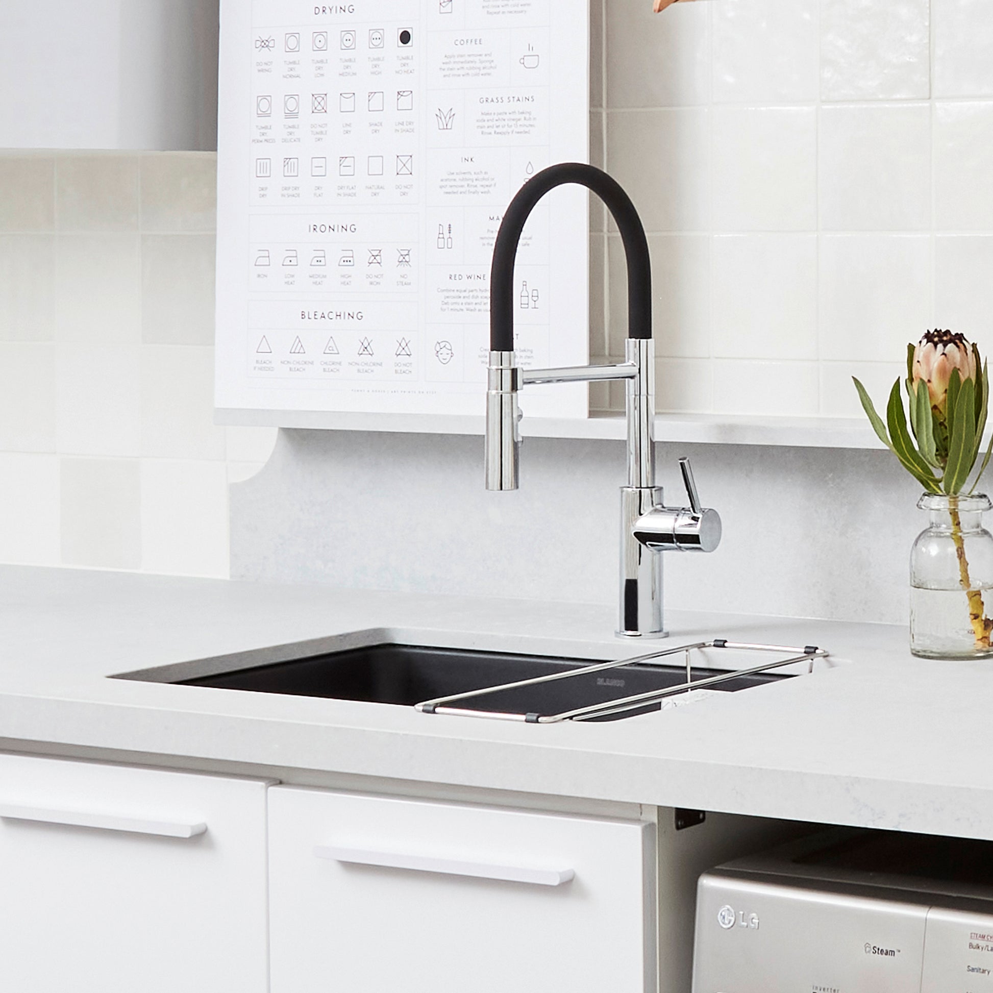 Chrome kitchen faucet with black flexible hose and lever handle mounted above undermount sink.