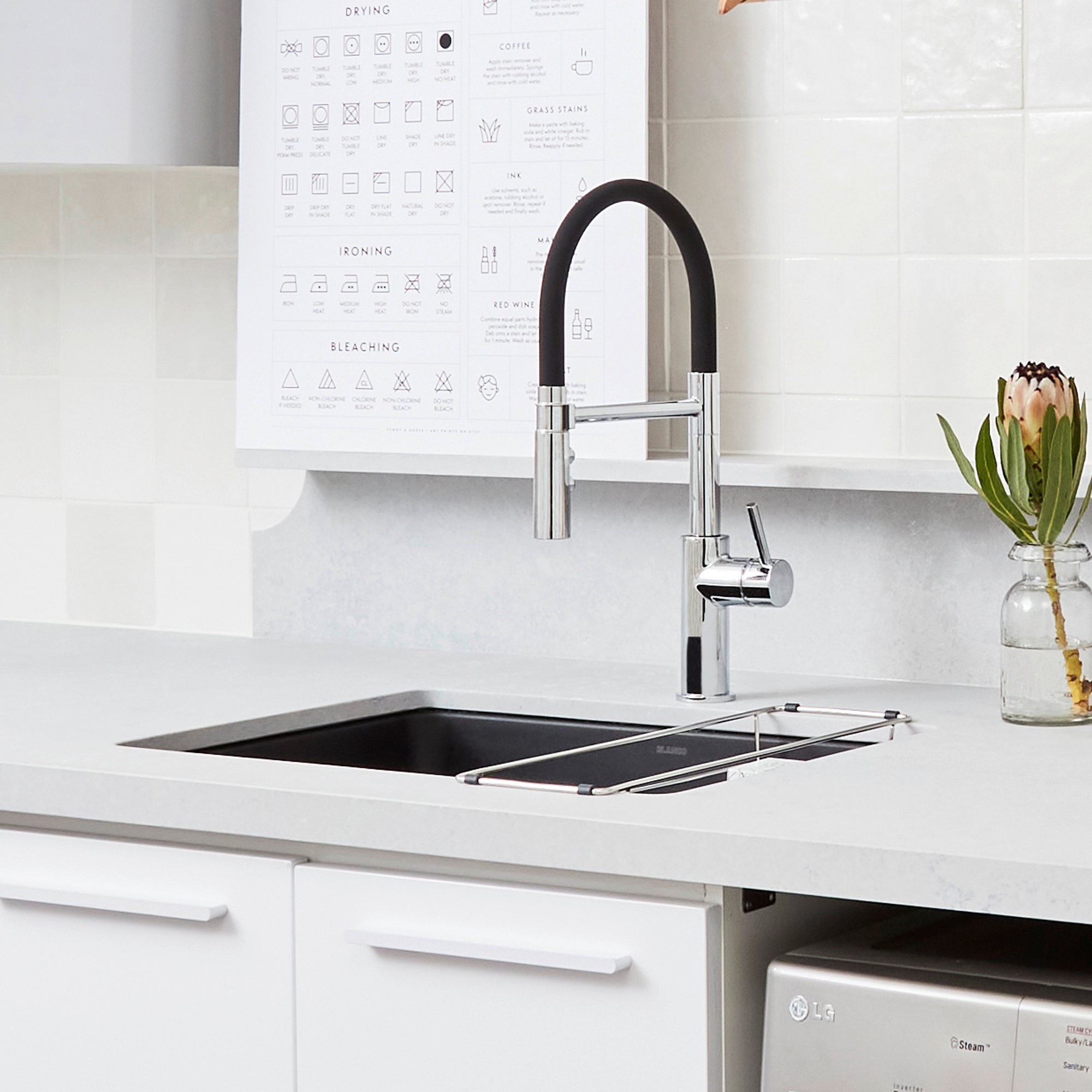 Chrome kitchen faucet with black flexible hose and lever handle mounted above undermount sink.