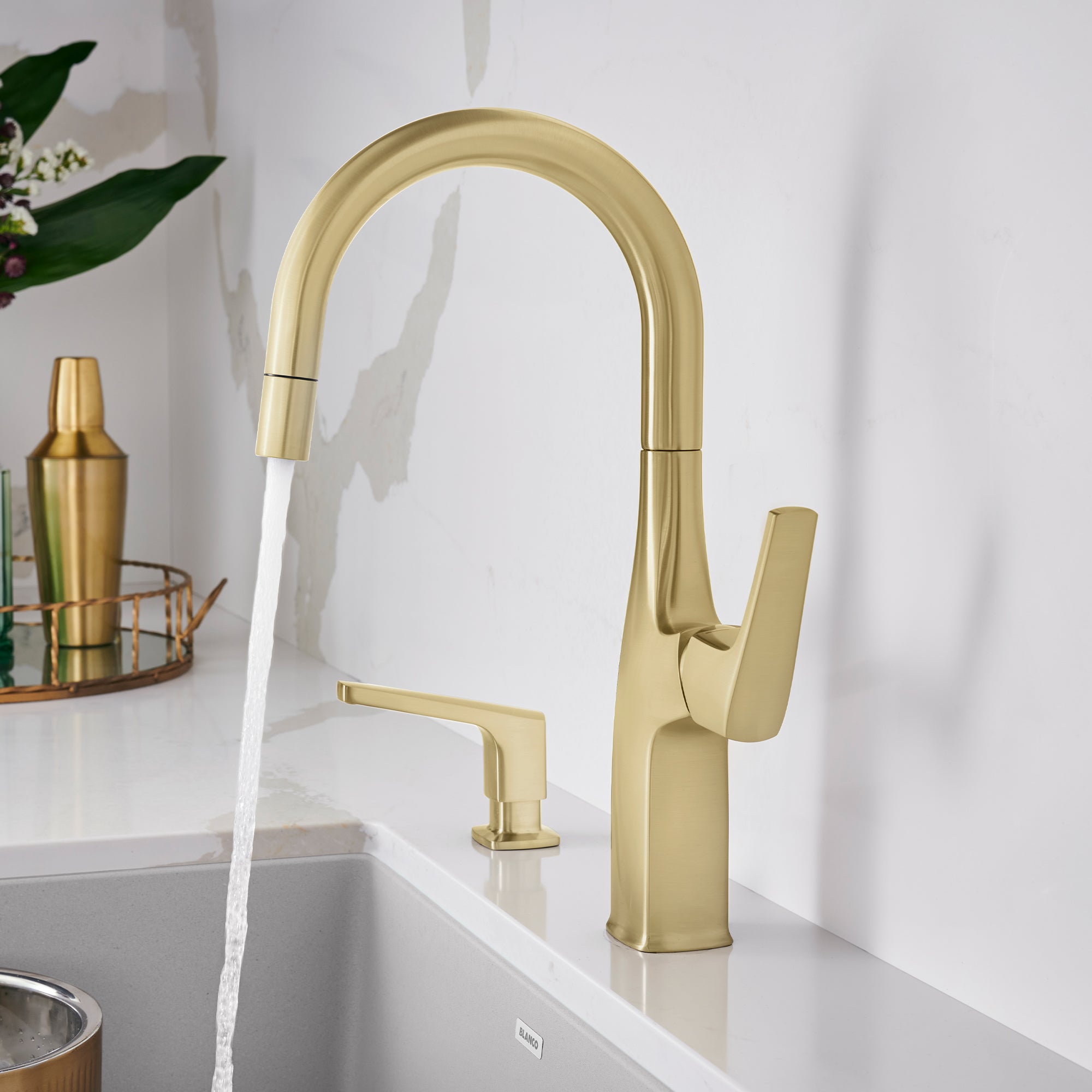 Satin gold bar faucet with curved spout, single lever handle, and water stream flowing into sink basin.
