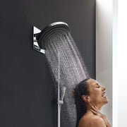 Chrome wallbar showerhead with 24-inch arm mounted on gray tile wall, dispensing water spray over person's head.