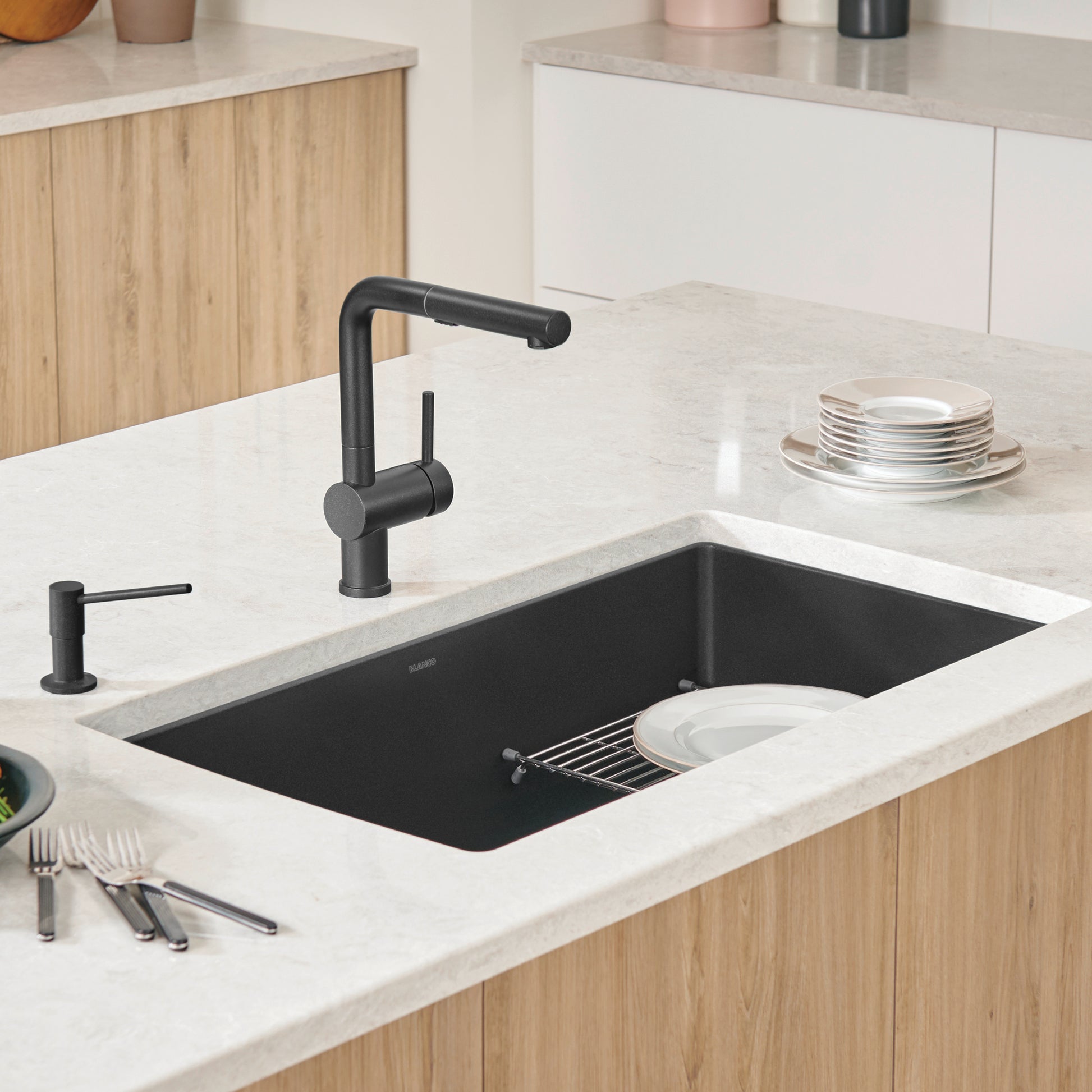 Anthracite undermount kitchen sink installed in white countertop with black faucet and wooden cabinetry.
