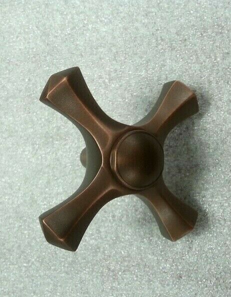 Coco bronze cross-shaped faucet handle with central circular knob and curved arms.