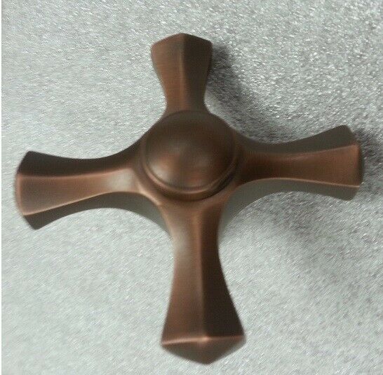 Coco bronze faucet handle with cross-shaped design and central knob, viewed from above.