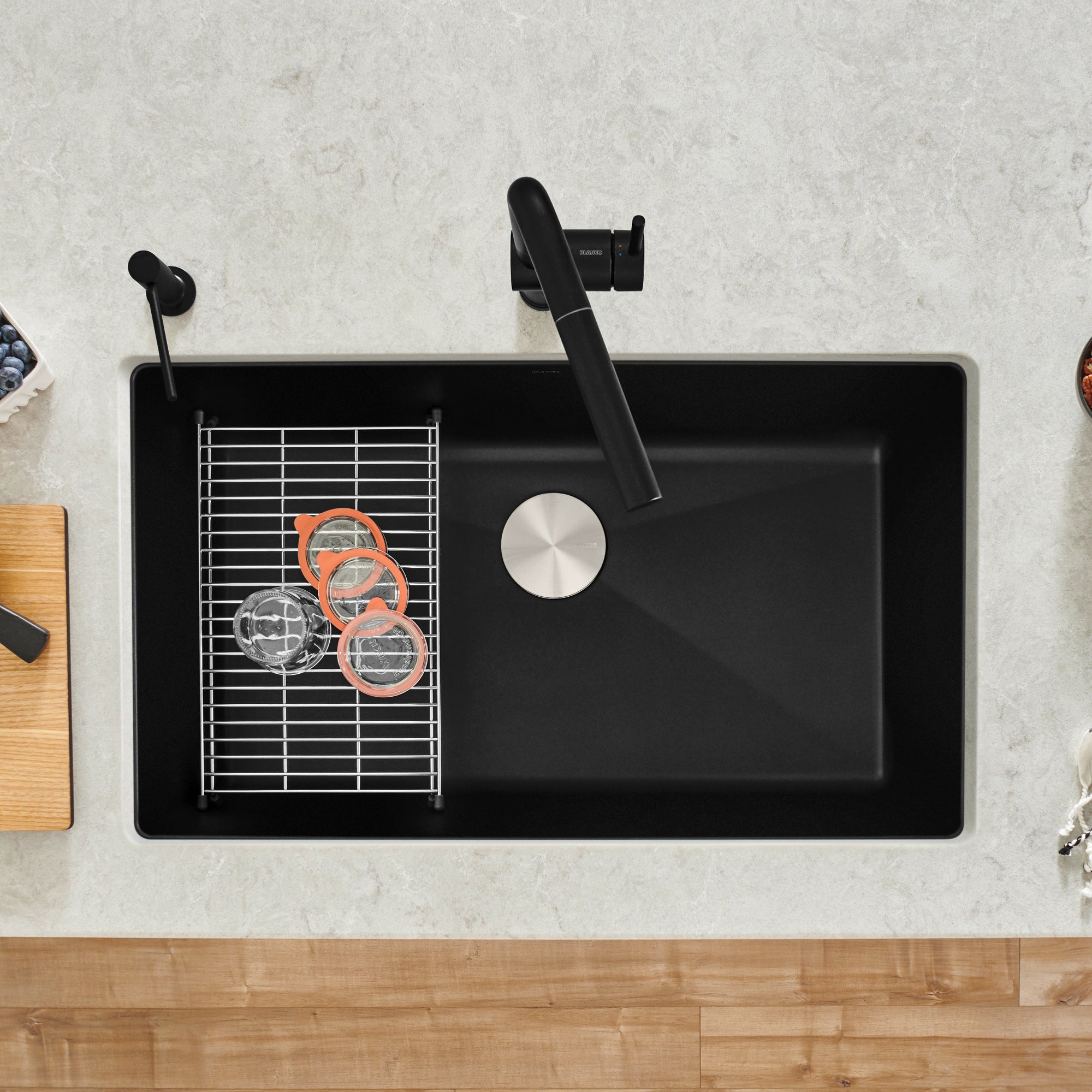 Coal black single basin kitchen sink with integrated drainboard, faucet, and accessories viewed from above.