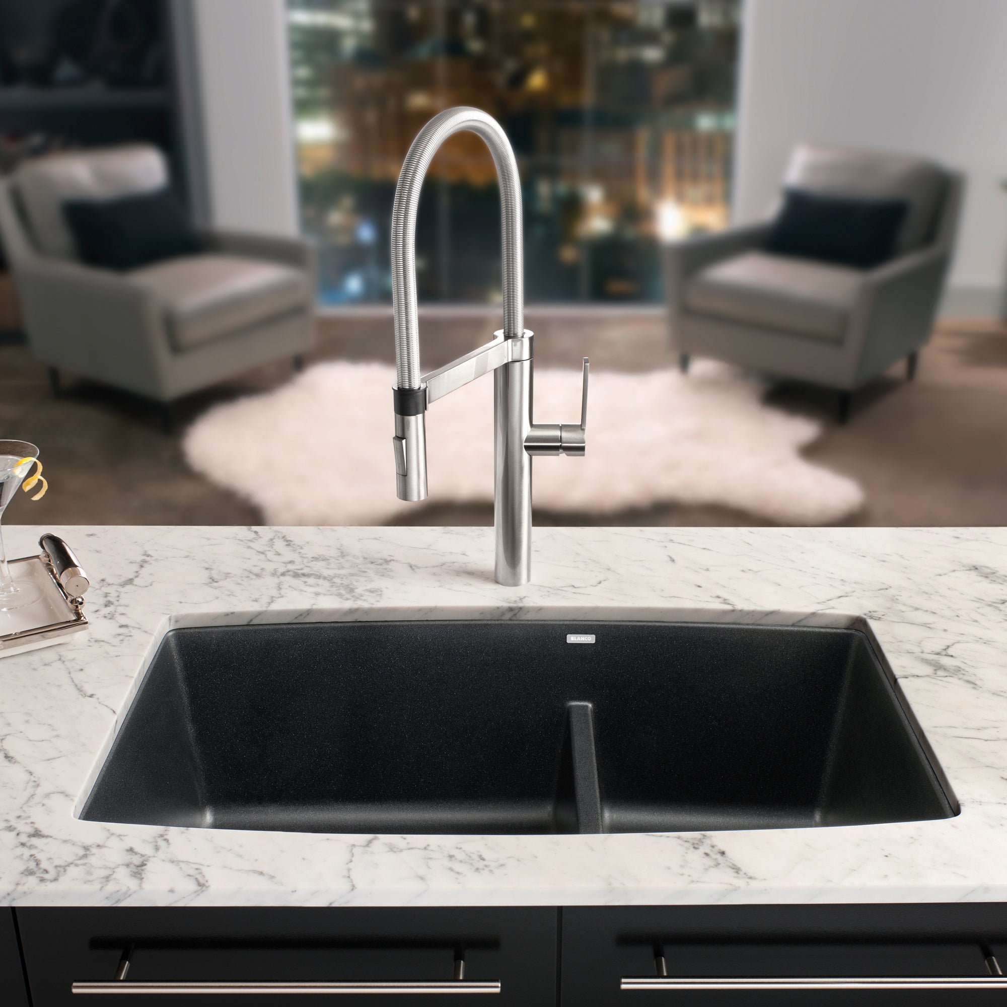 Anthracite undermount kitchen sink with divider and stainless steel pull-down faucet installed in marble countertop.