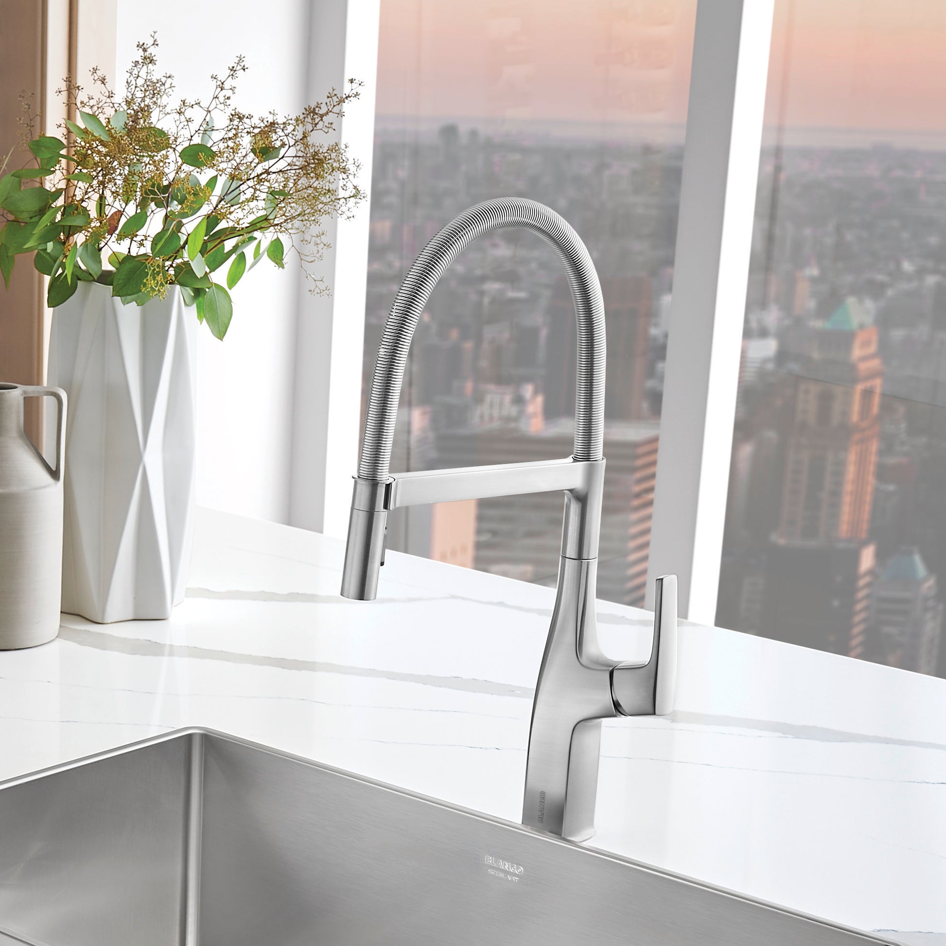 Stainless steel semi-pro kitchen faucet with pull-down sprayer and coiled hose, mounted above undermount sink.