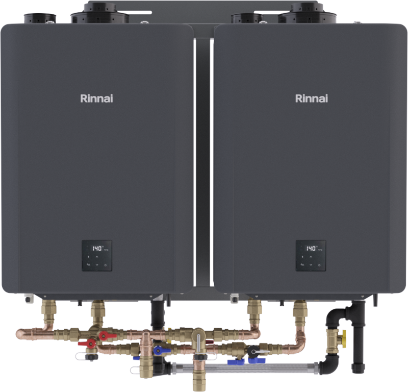 Two dark gray Rinnai tankless water heaters mounted side-by-side with digital controls and brass plumbing connections below.
