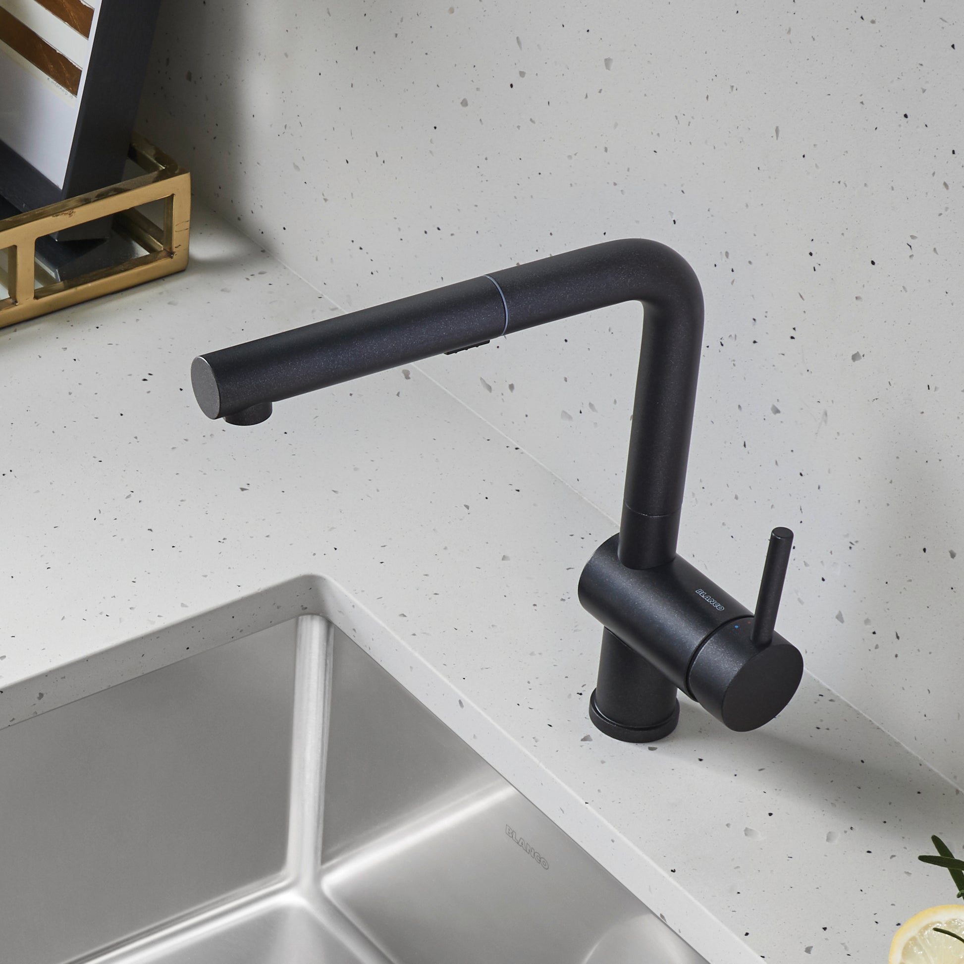Anthracite pull-out kitchen faucet with single lever handle mounted above white sink on speckled countertop.