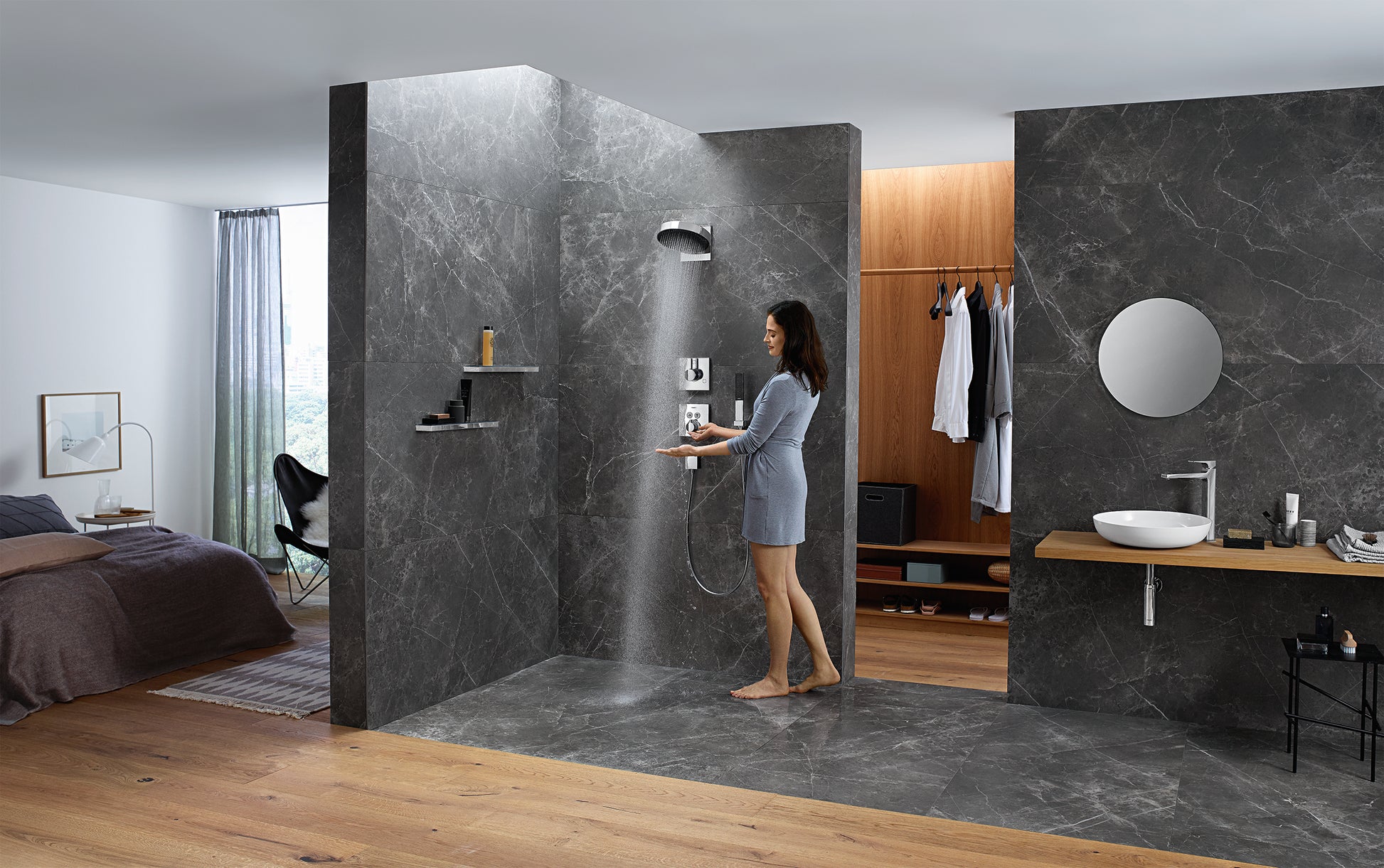 Matte black circular shower head mounted on dark marble wall with water stream visible during use.