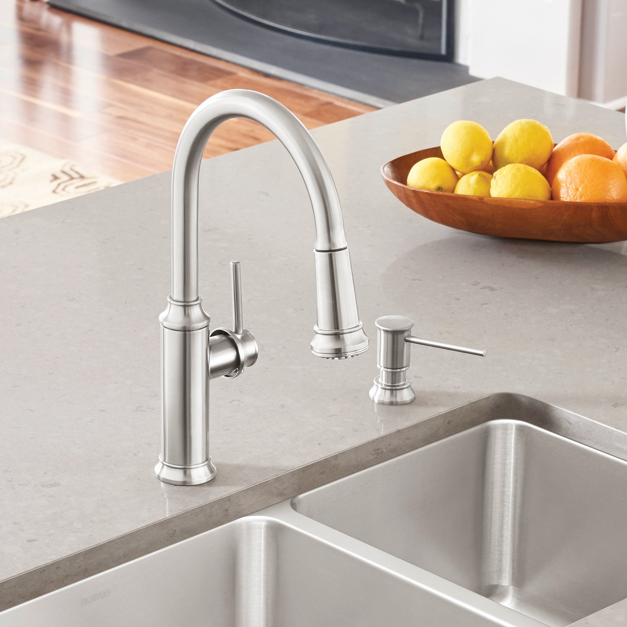 Stainless steel pull-down kitchen faucet with curved spout and lever handle above double sink basin.