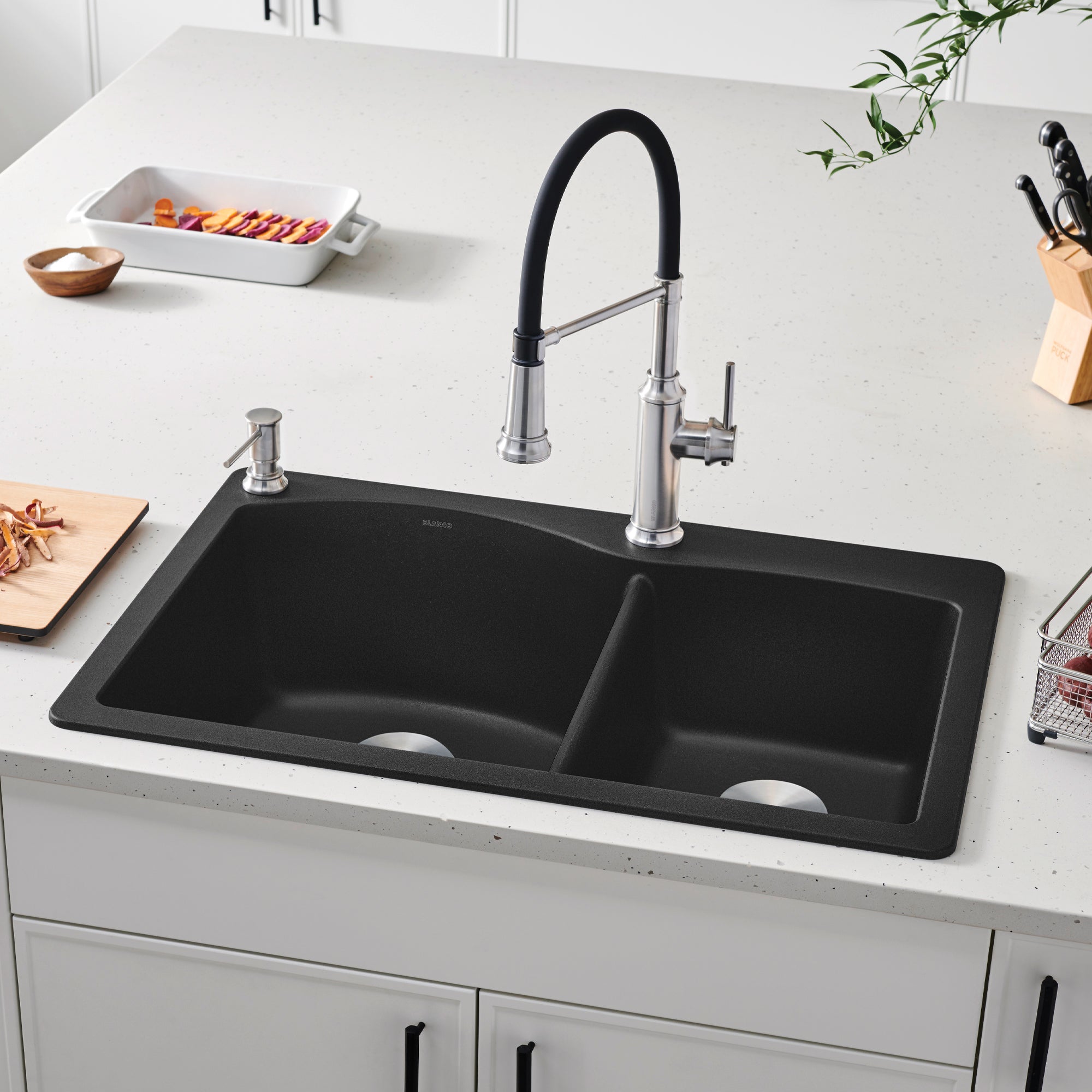 Anthracite drop-in kitchen sink with two bowls, chrome faucet with black handle, and soap dispenser installed in white counte