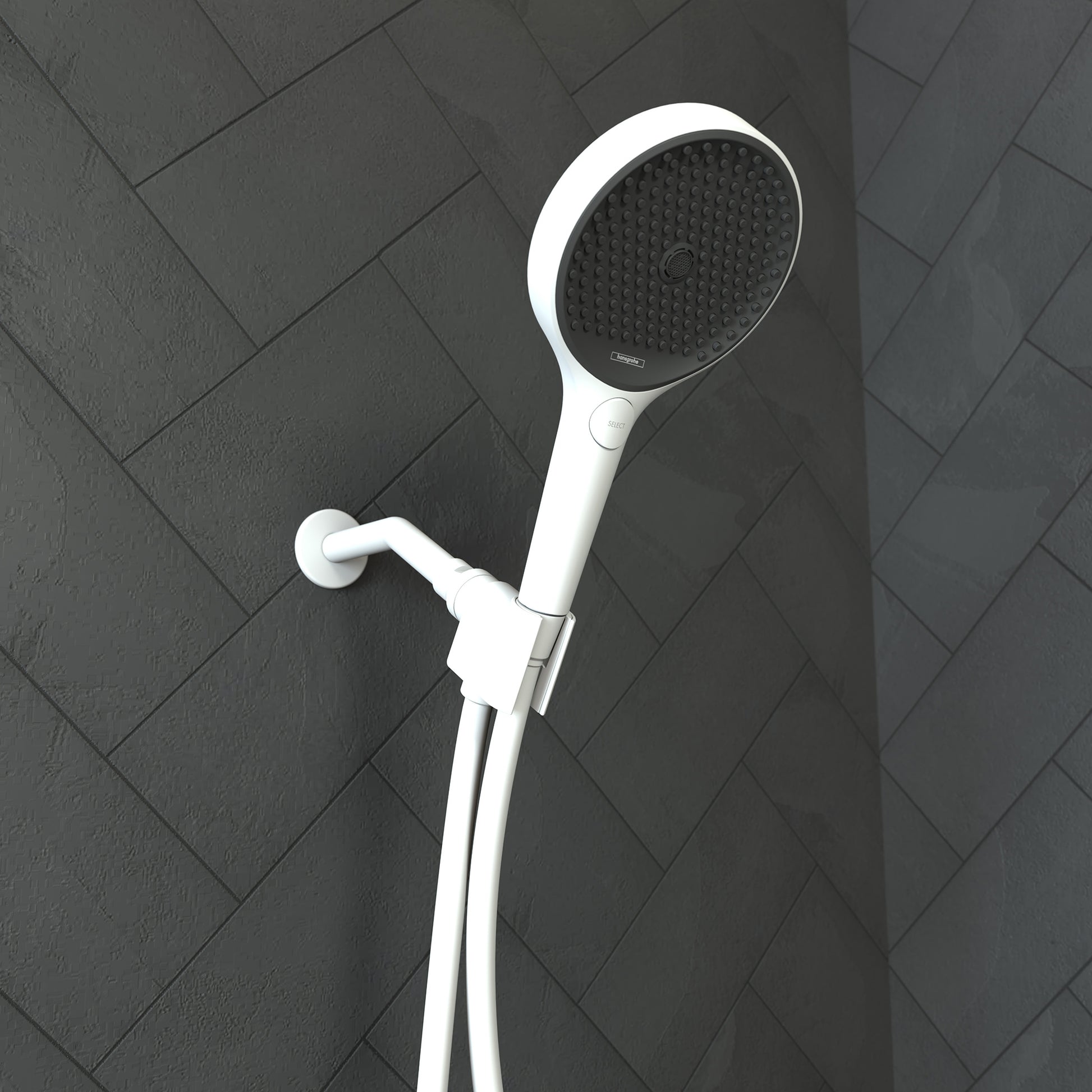 Matte white handheld showerhead with black perforated face mounted on wall bracket with hose against dark tile.