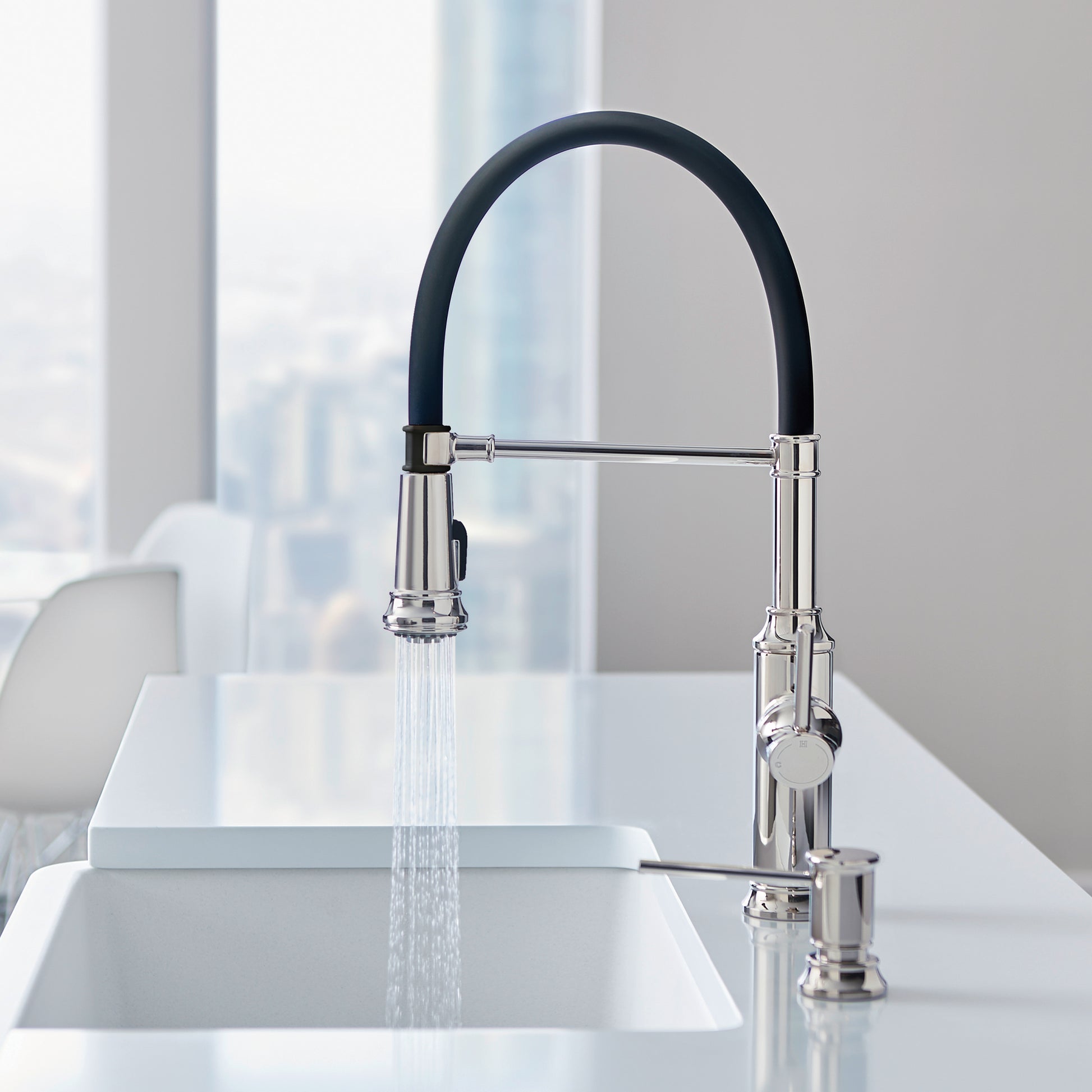 Chrome kitchen faucet with black curved pull-down sprayer head mounted above white sink basin.