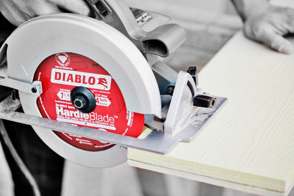 Red and white Diablo HardieBlade circular saw blade mounted on circular saw cutting through light wood.
