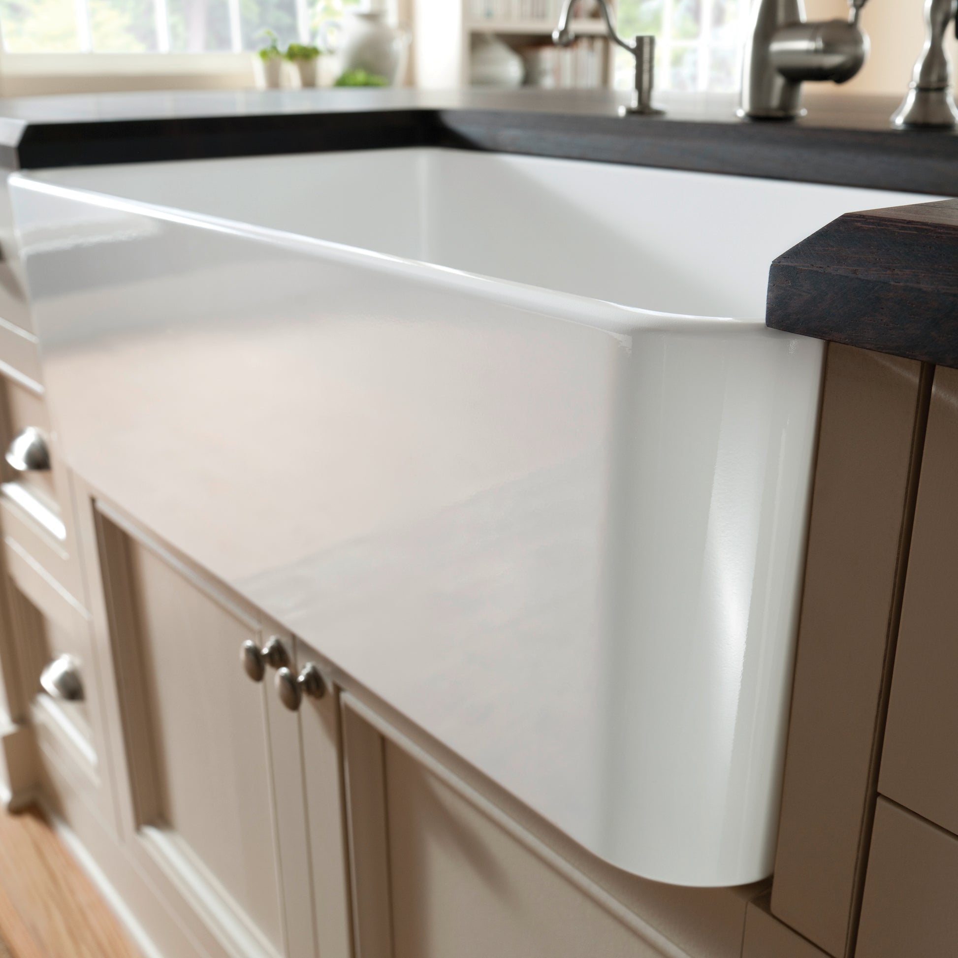 White farmhouse apron front sink with single basin installed in kitchen cabinet.