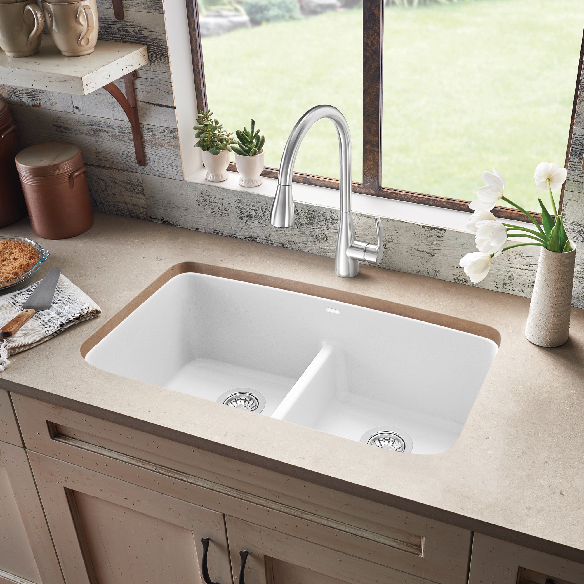 White Silgranit double undermount sink with low divider and chrome faucet in kitchen countertop.