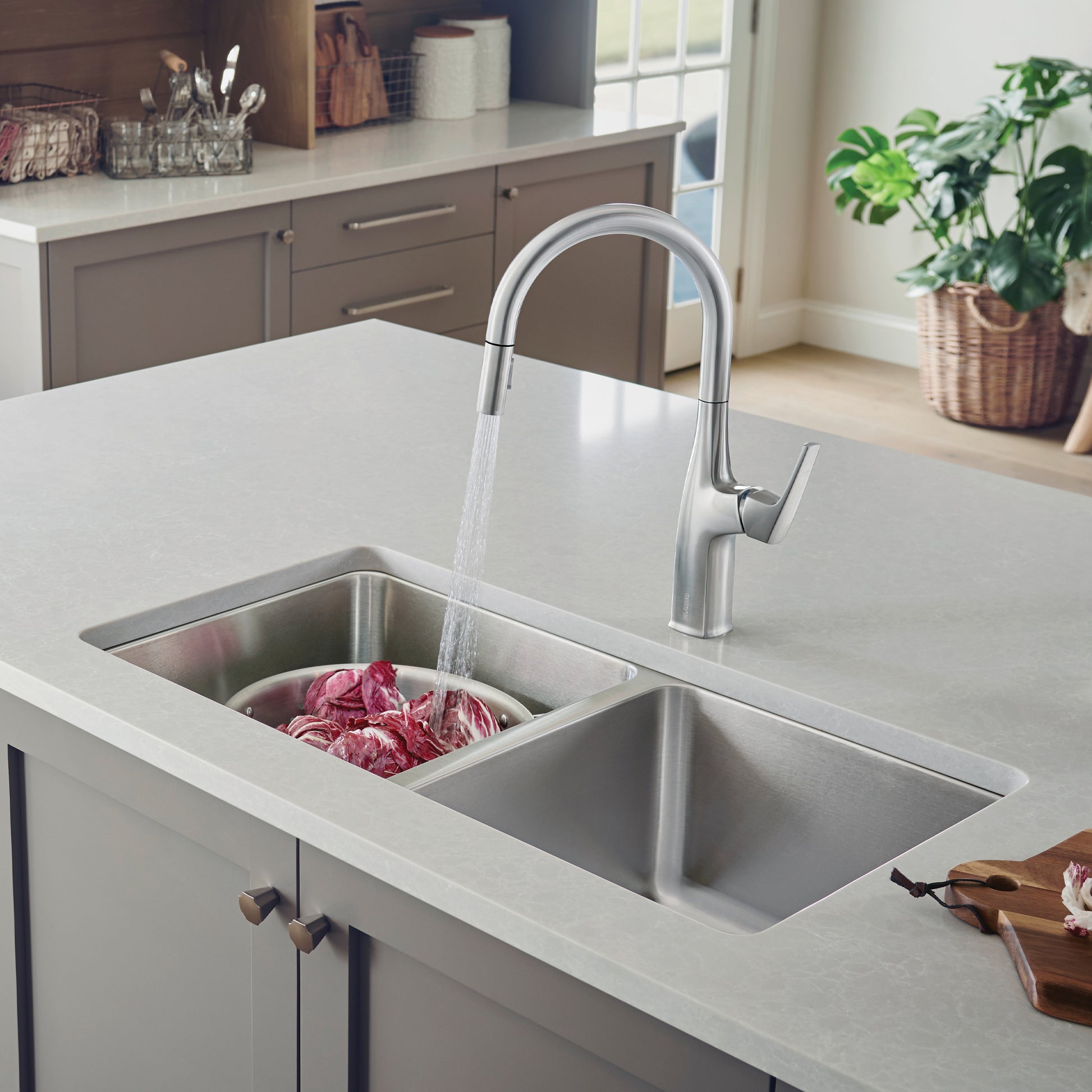 Stainless steel undermount double bowl sink with chrome pull-down faucet installed in white countertop.