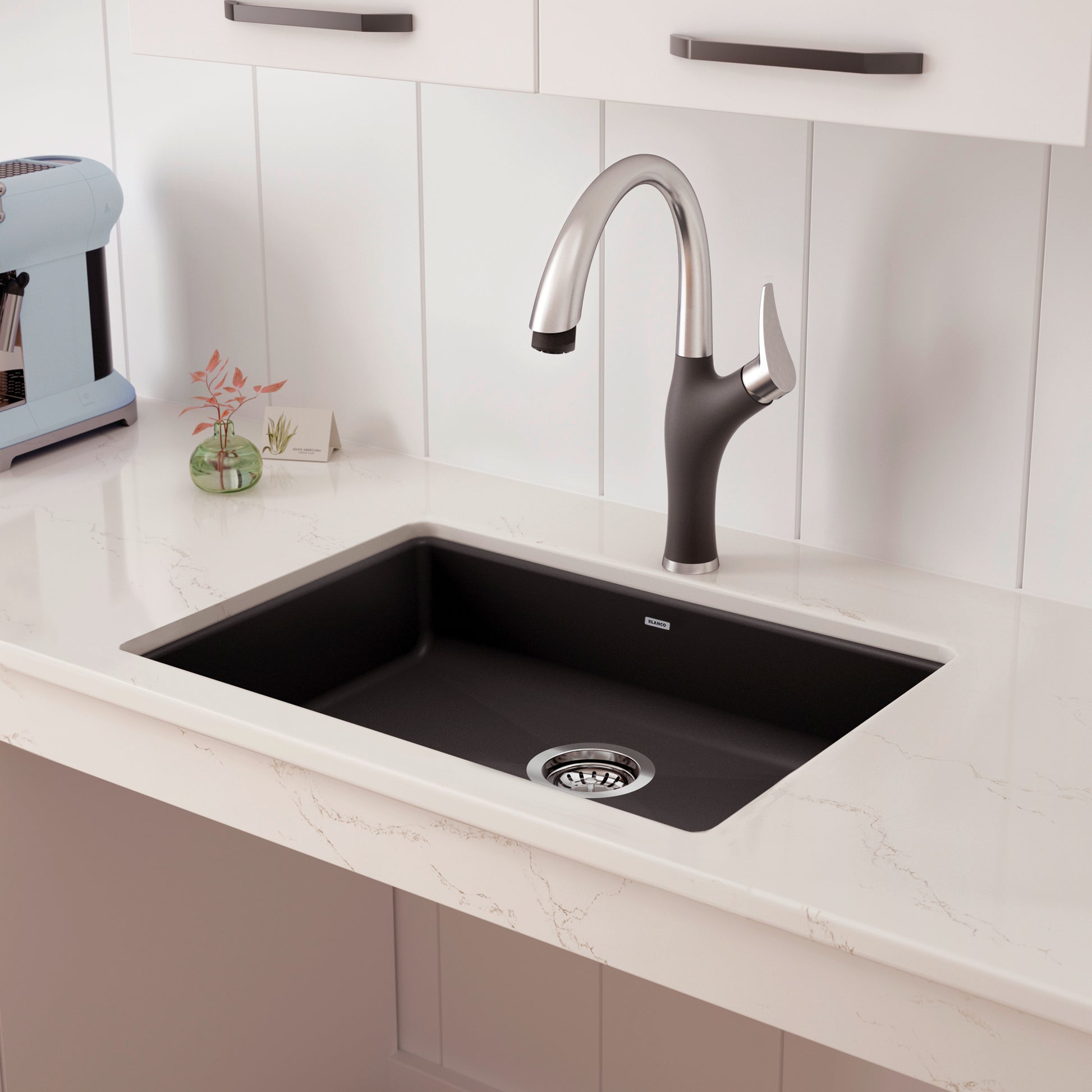 Black undermount kitchen sink with single chrome and black pull-down faucet installed in white countertop.