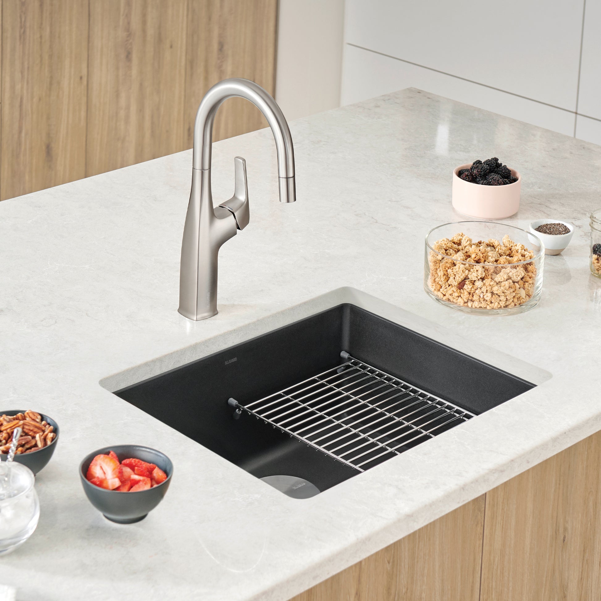 Coal black single bowl undermount kitchen sink with stainless steel pull-down faucet, installed in light countertop.